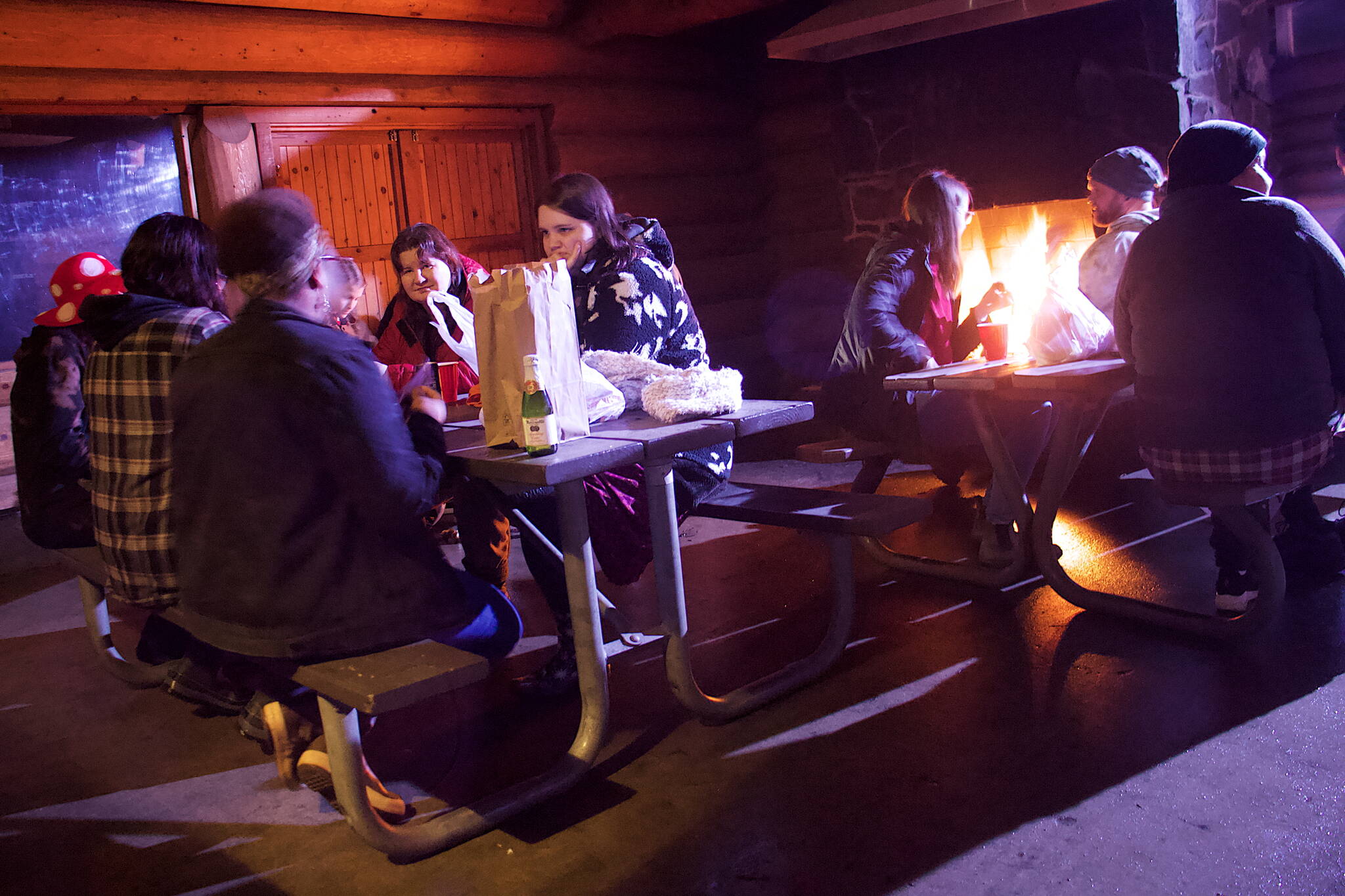 People gather for a newly organized communal Friendsgiving celebration at the log cabin at Savikko Park on Thursday night. (Mark Sabbatini / Juneau Empire)