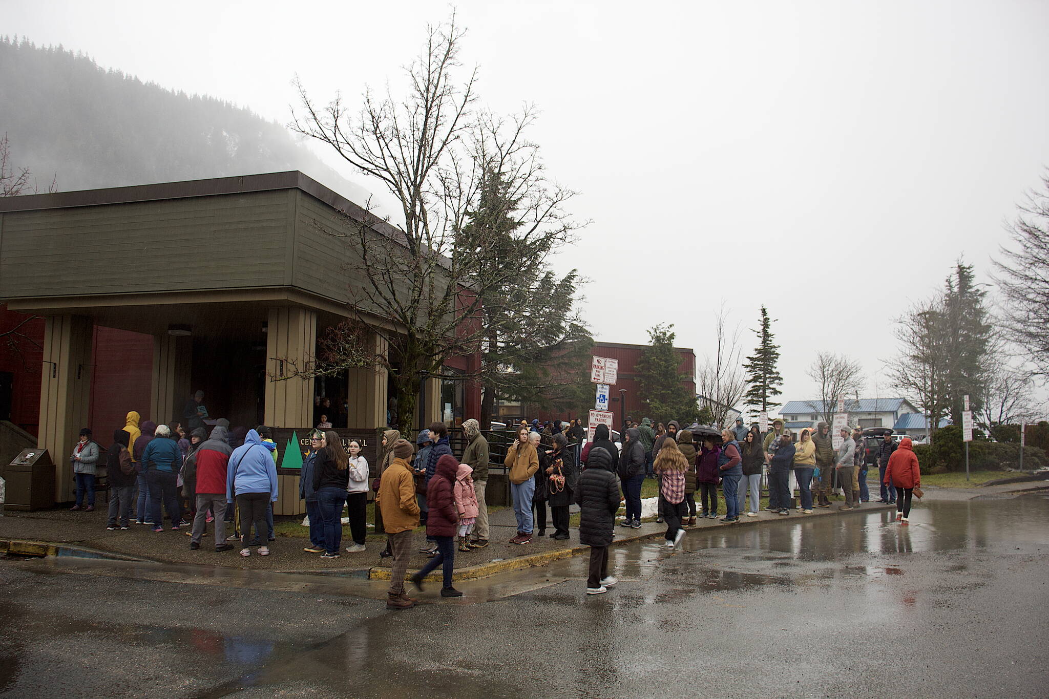 A few dozen people wait in the rain outside Centennial Hall for the start of the Juneau Public Market just before noon on Friday. (Mark Sabbatini / Juneau Empire)