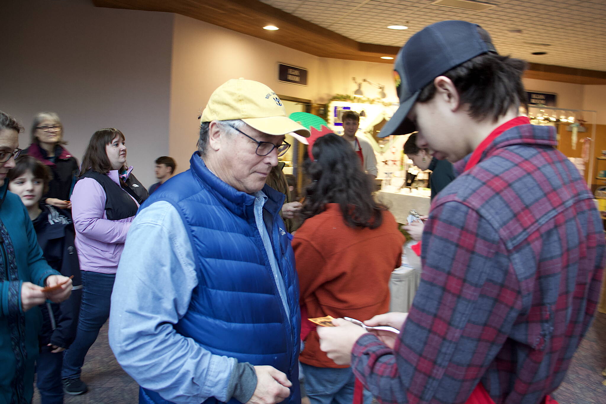 Larry Gamez (left) has his admission ticket to the Juneau Public Market punched on Friday. He was the second in line to enter the market at Centennial Hall, arriving an hour early. (Mark Sabbatini / Juneau Empire)