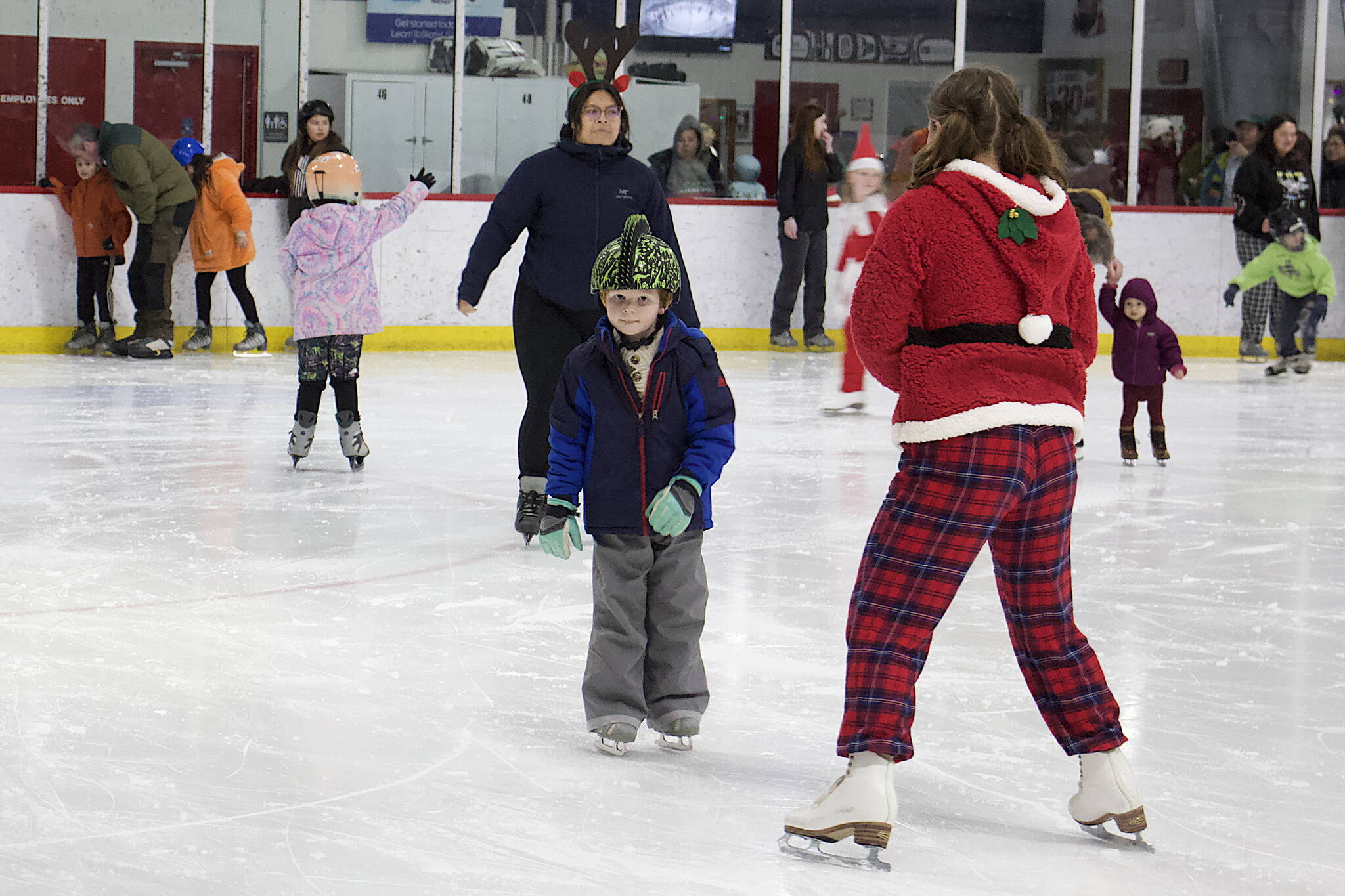 One of Santa’s helpers coaxes a skater along the ice during the annual Santa Skate at Treadwell Arena on Friday night.(Mark Sabbatini / Juneau Empire)