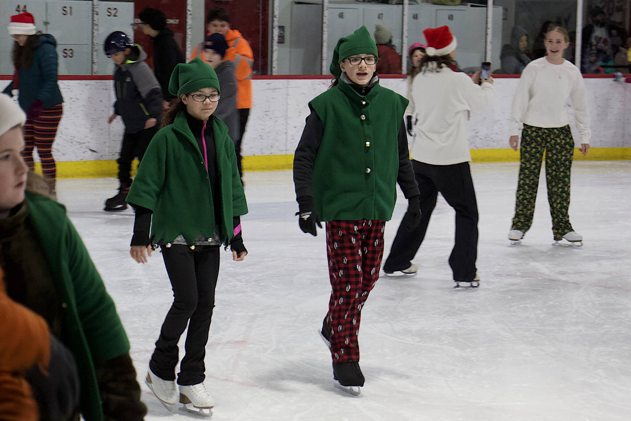 A pair of Santa’s elves get into the spirit of the season during the annual Santa Skate at Treadwell Arena on Friday night. (Mark Sabbatini / Juneau Empire)