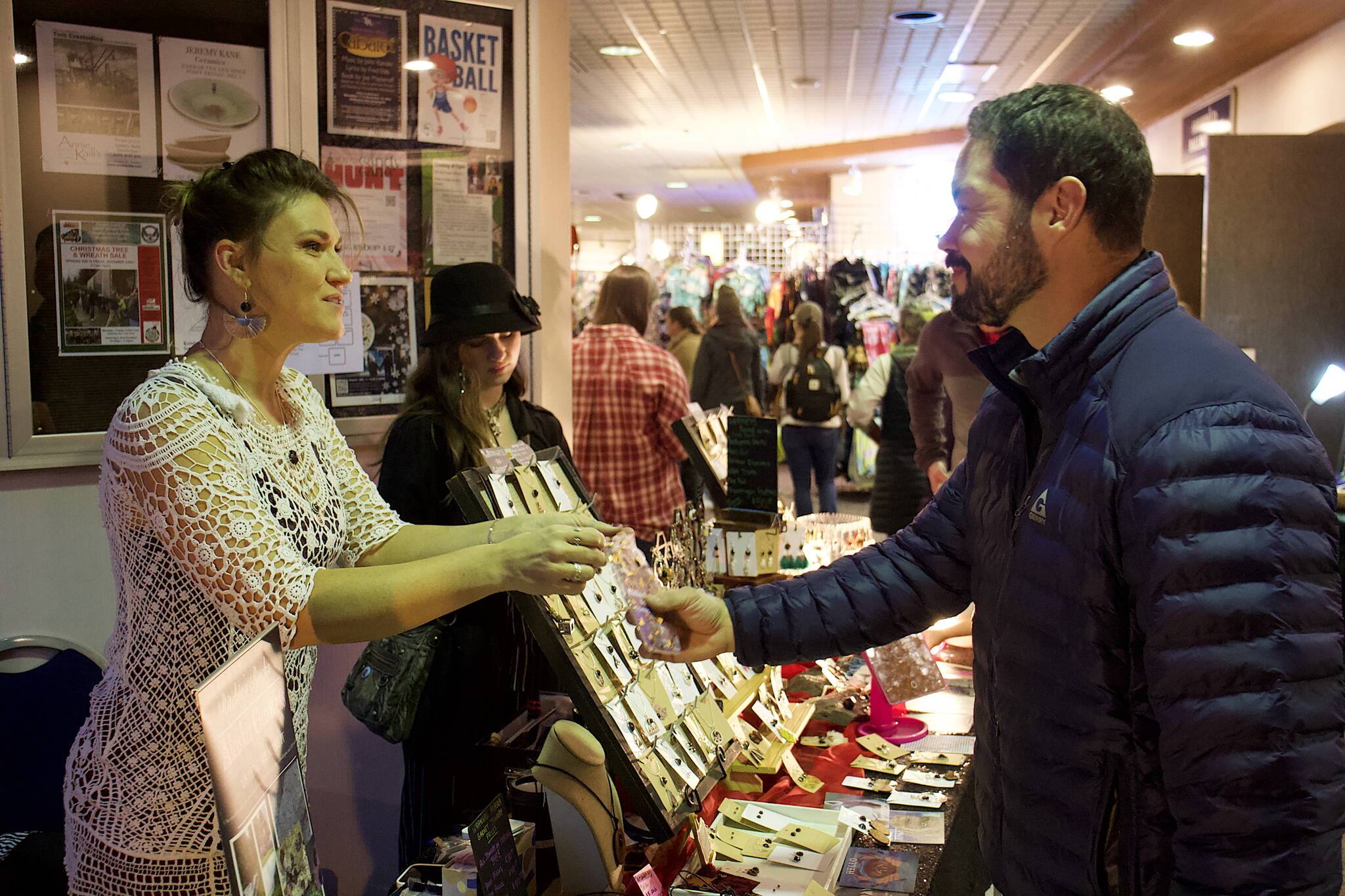 Bonnie Ritchie (left), owner of Ritchie’s Rocks in Wrangell, hands a purchase to a customer at the Juneau Public Market at Centennial Hall on Saturday. (Mark Sabbatini / Juneau Empire)