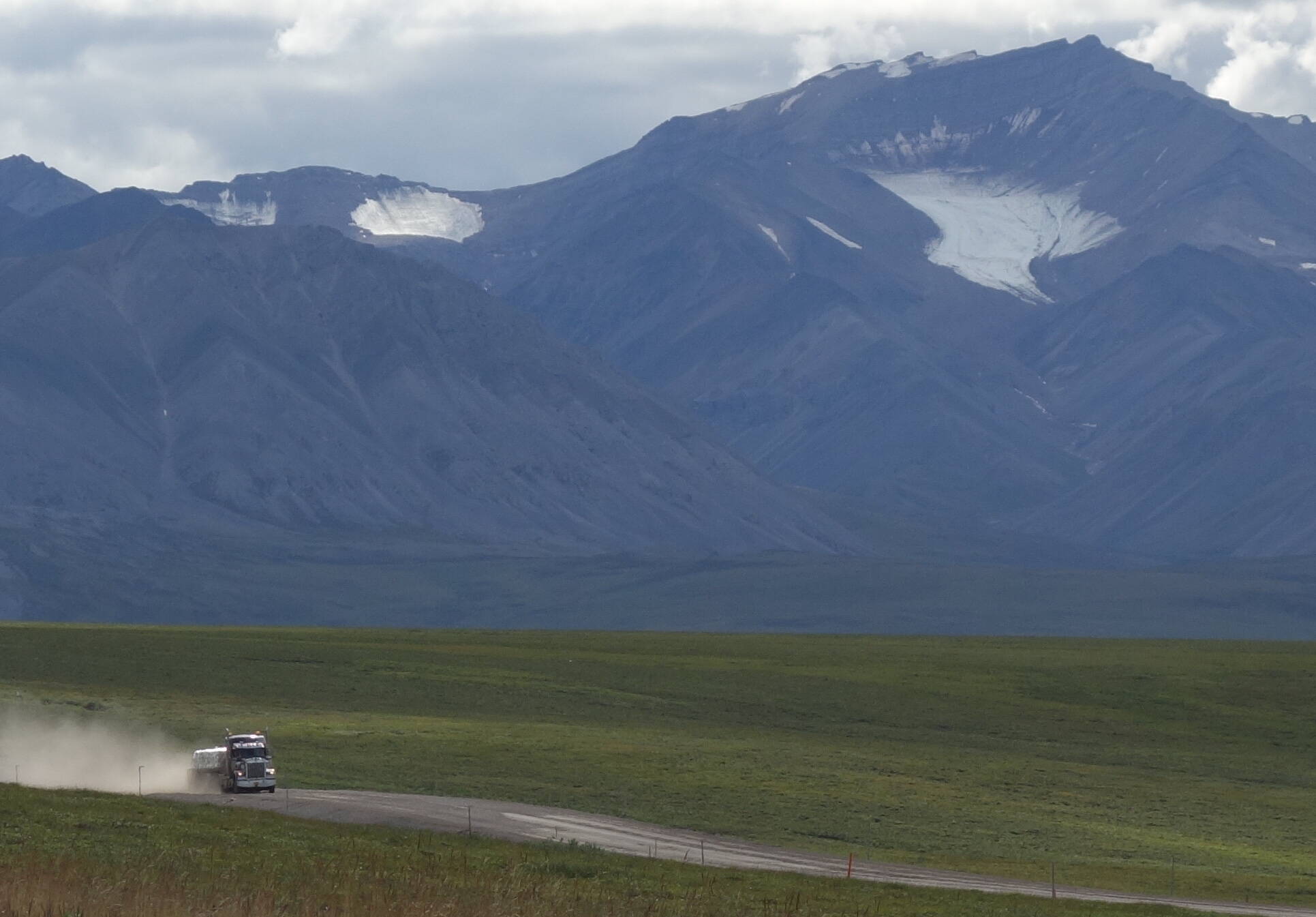 A trucker drives the Dalton Highway toward Prudhoe Bay beneath the withering Gates Glacier. (Photo by Ned Rozell)