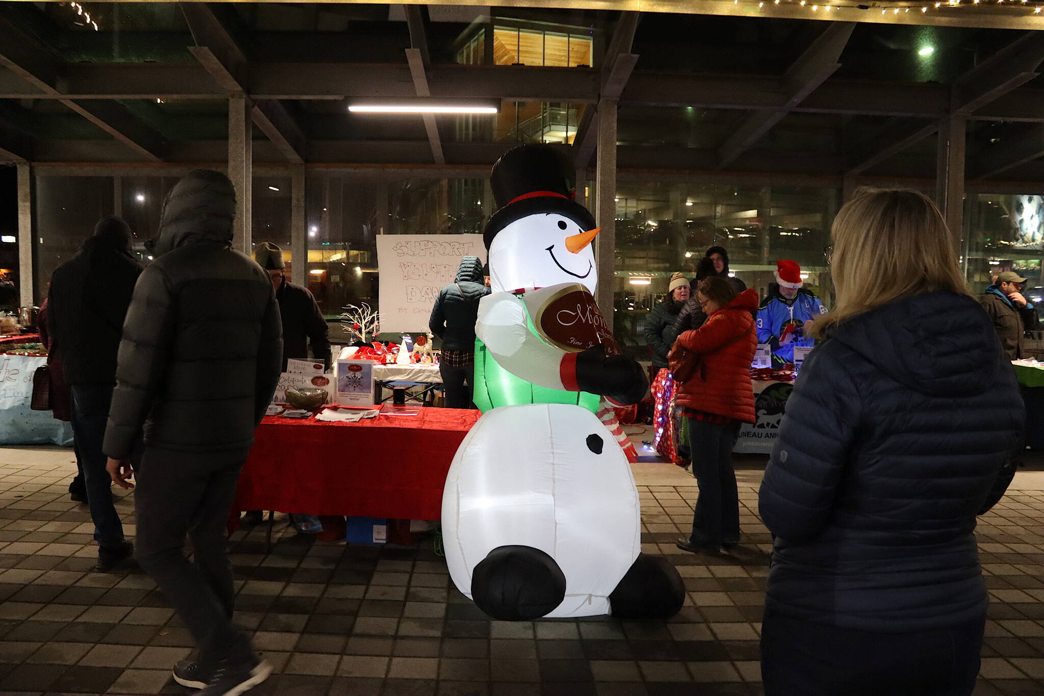 A giant inflatable snowman greets shoppers in front of a row of vendors selling crafts at Sealaska Heritage Plaza during Gallery Walk on Friday. (Mark Sabbatini / Juneau Empire)