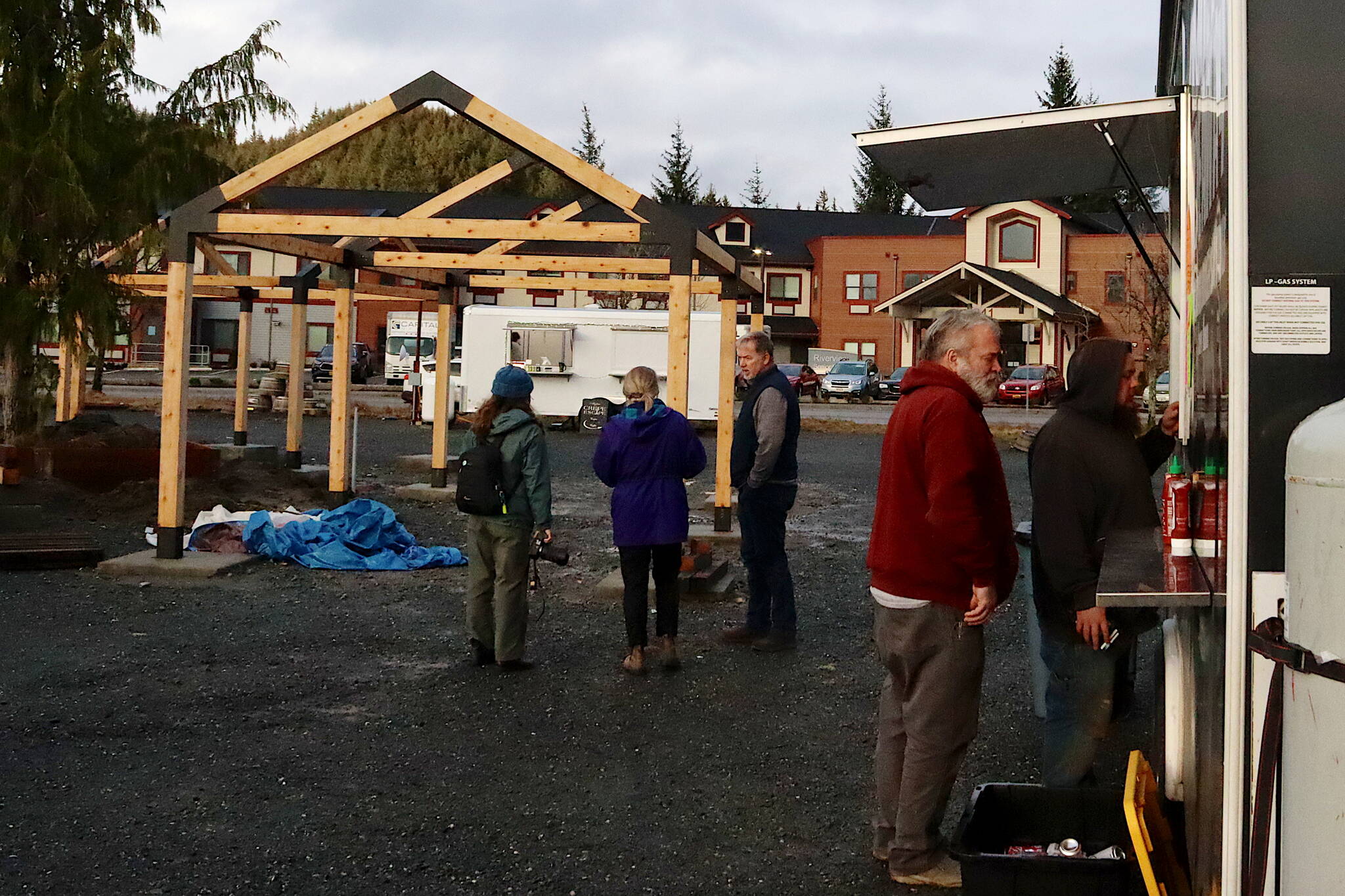 Ron Ekis (wearing red) and Dakota Brown order from Devils Hideaway at the new Vintage Food Truck Park as Marty McKeown, owner of the property, shows seating facilities still under construction to other local media members on Wednesday. (Mark Sabbatini / Juneau Empire)