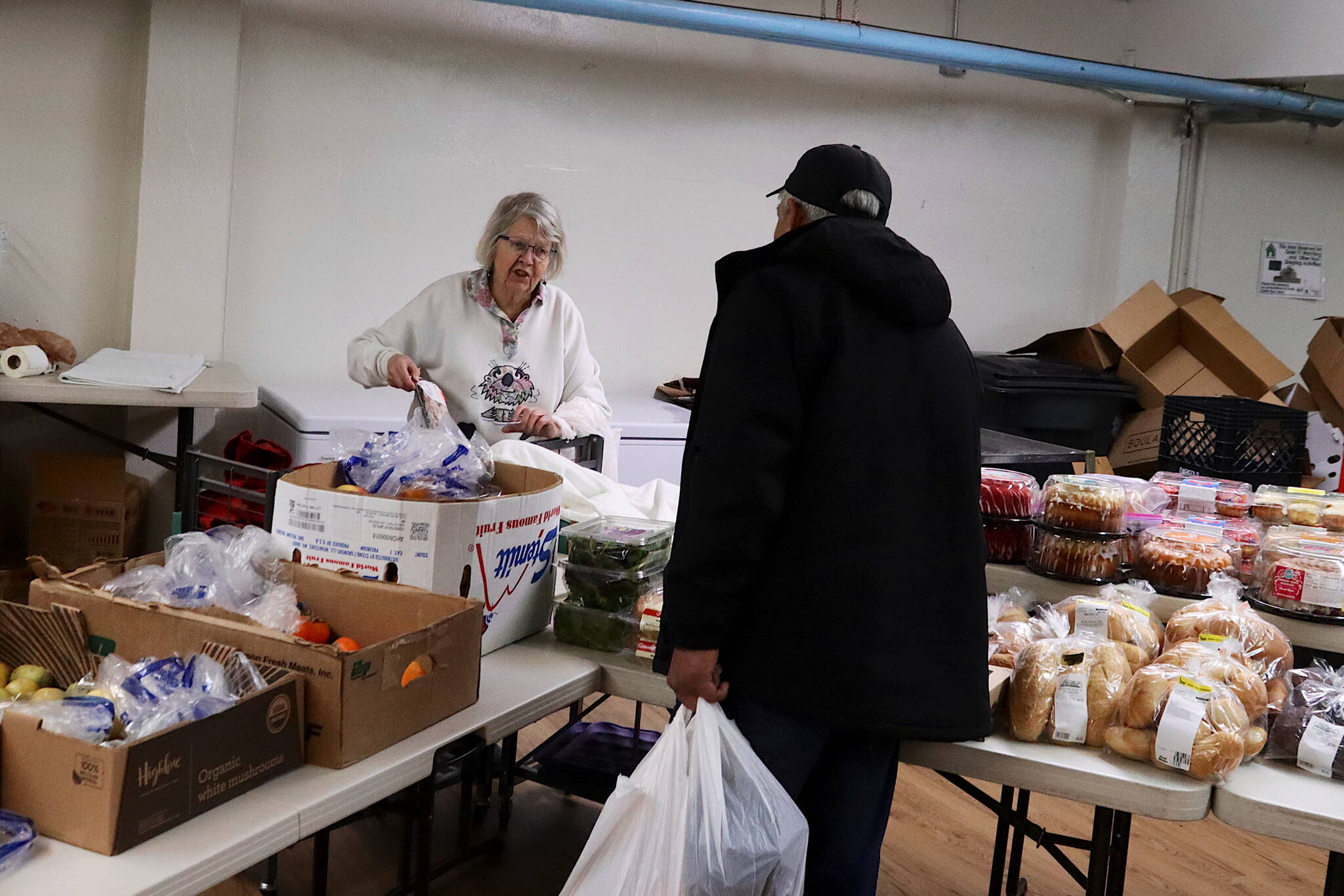Sylvia Geraghty helps a customer during the weekly food pantry at Resurrection Lutheran Church on Tuesday. (Mark Sabbatini / Juneau Empire)