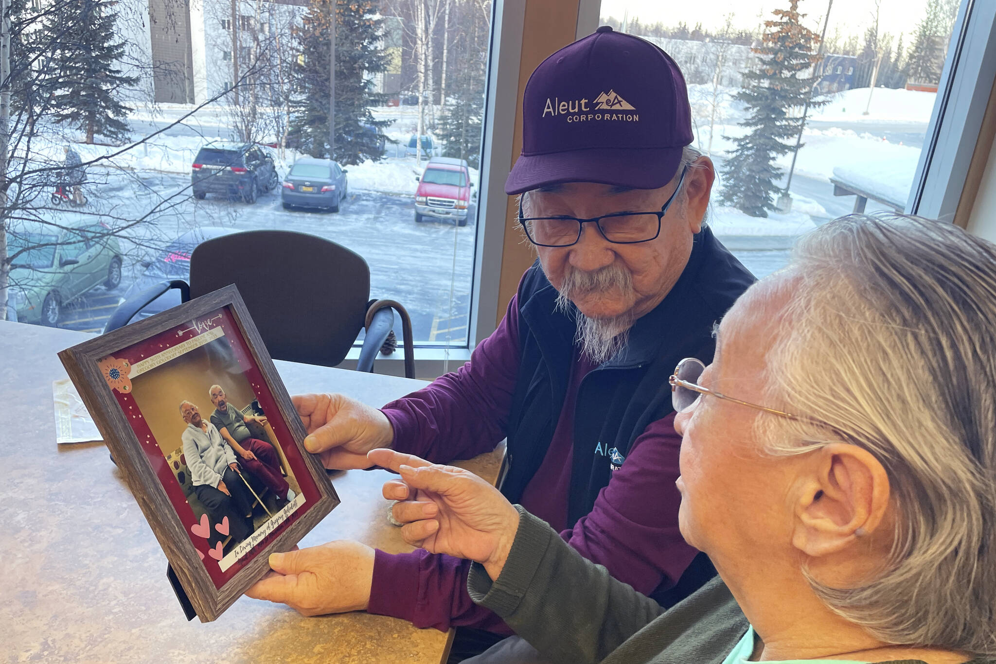 George Kudrin, left, and Pauline Golodoff hold a photo of Pauline and her late husband, Gregory Golodoff, Friday, Dec. 1, 2023, in Anchorage, Alaska. Gregory and his sister Elizabeth Golodoff Kudrin, George’s late wife, were the last two living residents of Attu, Alaska, whose entire population was captured by the Japanese during World War II and sent to Japan until being liberated after the war. The community of Attu was not rebuilt, and residents were resettled elsewhere, mostly in Atka, Alaska. (AP Photo/Mark Thiessen)