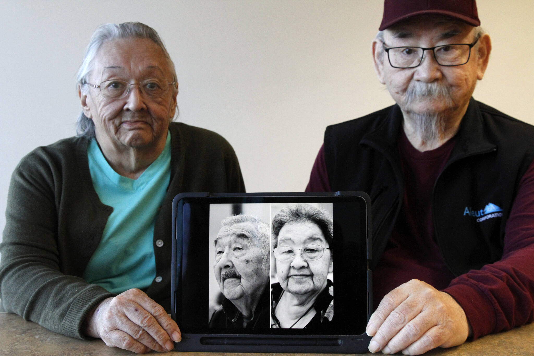 Pauline Golodoff, left, and George Kudrin hold an iPad featuring images of their deceased spouses, Gregory Golodoff and Elizabeth Golodoff Kurdrin, Friday, Dec. 1, 2023, in Anchorage, Alaska. Gregory and Elizabeth were the last two living residents of Attu, Alaska, whose entire population was captured by the Japanese during World War II and sent to Japan until being liberated after the war. The community of Attu was not rebuilt, and residents were resettled elsewhere, mostly in Atka, Alaska. (AP Photo/Mark Thiessen)