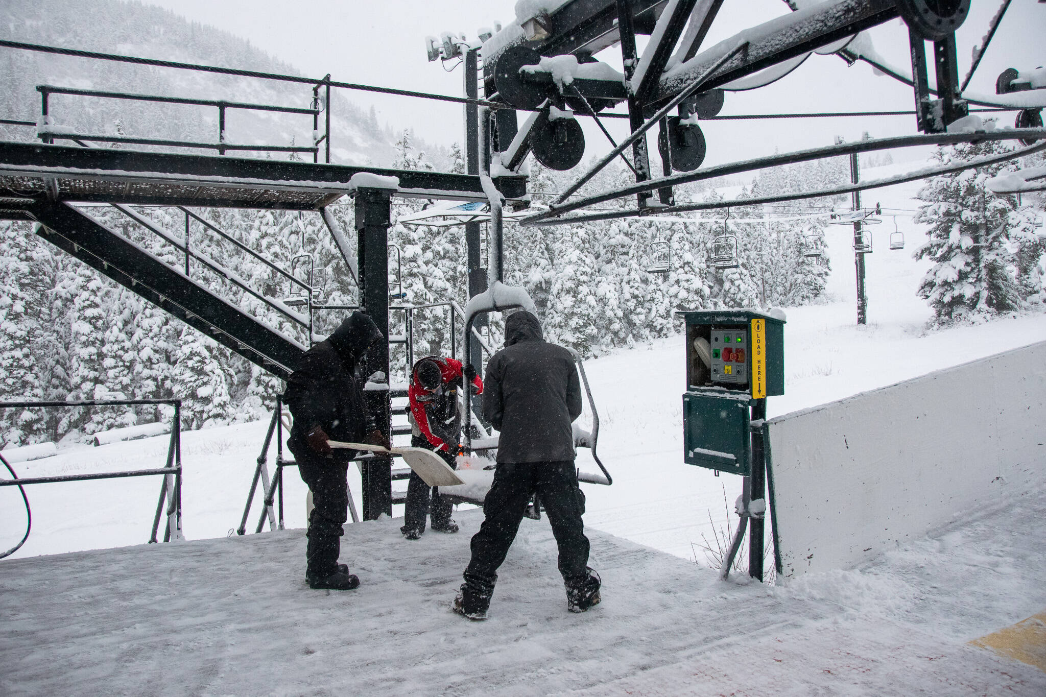 Eaglecrest Ski Area employees clear snow from a lift chair on Sunday, when conditions for opening by this weekend seemed promising. But warmer and wet weather this week means the bottom of the mountain is still not ready for operation, although Eaglecrest Grill will be open this weekend for people wanting to access snow on the upper part of the mountain on their own. (Photo courtesy of Eaglecrest Ski Area.)