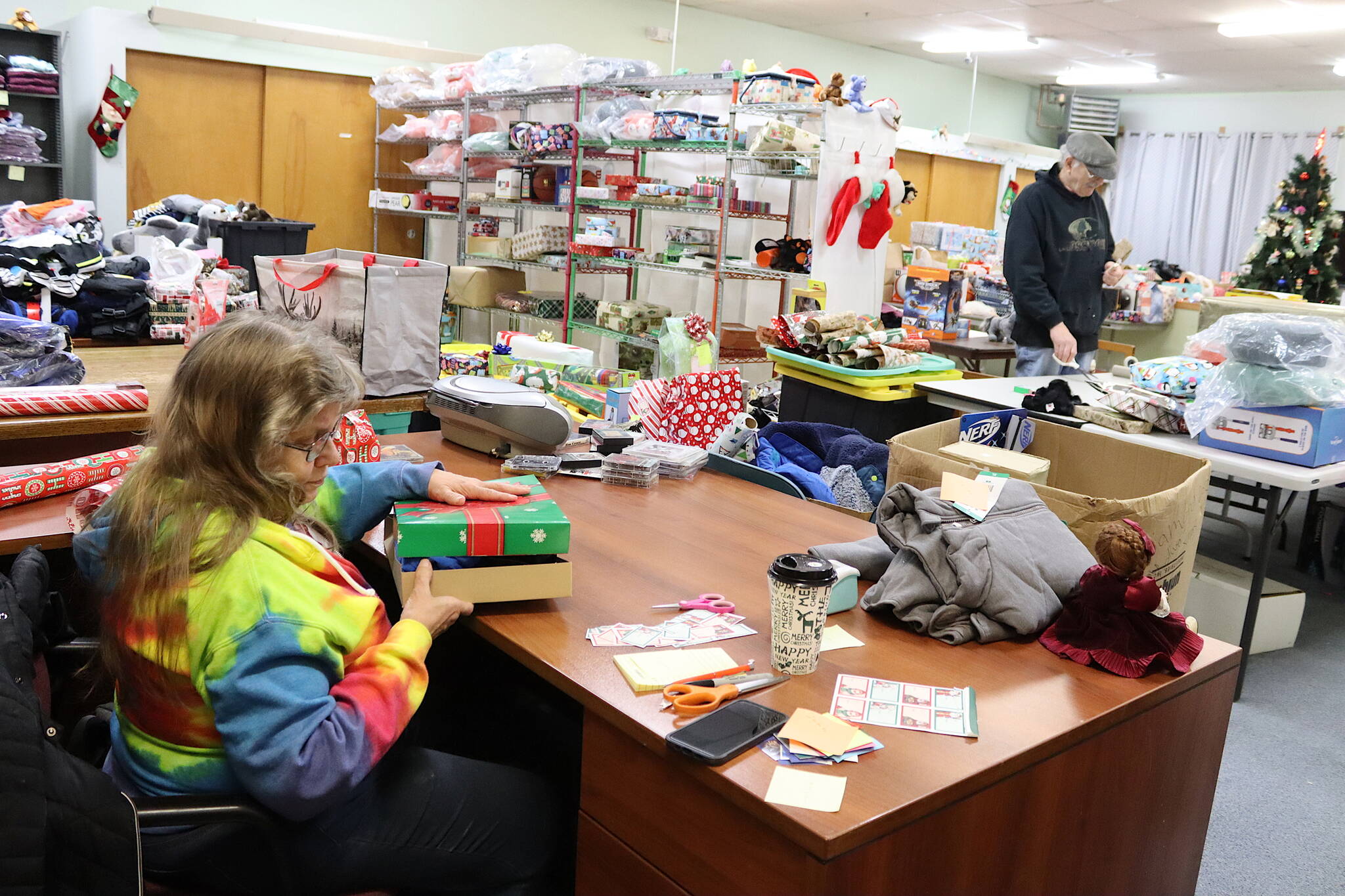 Martha Crockroft (foreground) and Jeff Marks wrap gifts for the annual Adopt-A-Family Christmas Gift Program at the St. Vincent de Paul Juneau complex on Saturday. (Mark Sabbatini / Juneau Empire)