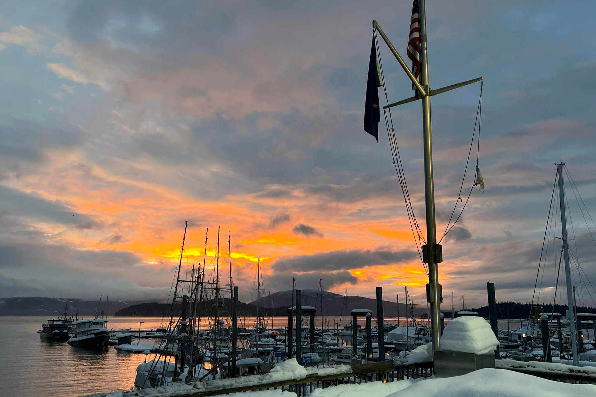The sun sets on snow-covered boats in Auke Bay on Jan. 10, 2022. On Jan. 1, 2024, most local docks and harbors fees will increase 9%. (Photo by the City and Borough of Juneau Docks and Harbors Department)