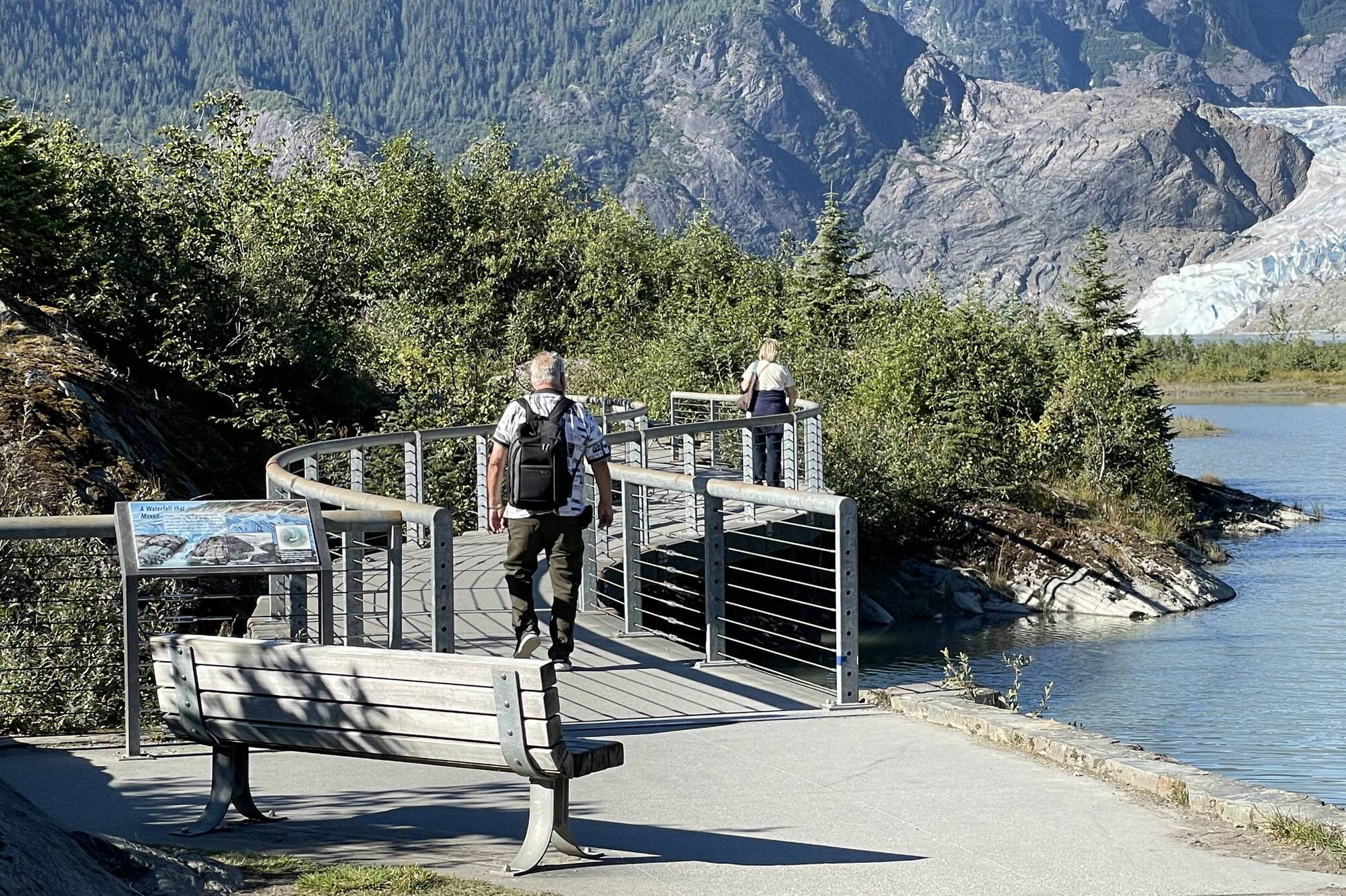 Two visitors walk on the Photo Point Trail footbridge at the Mendenhall Glacier Recreation Area on Aug. 27, 2023. (Photo by Laurie Craig)