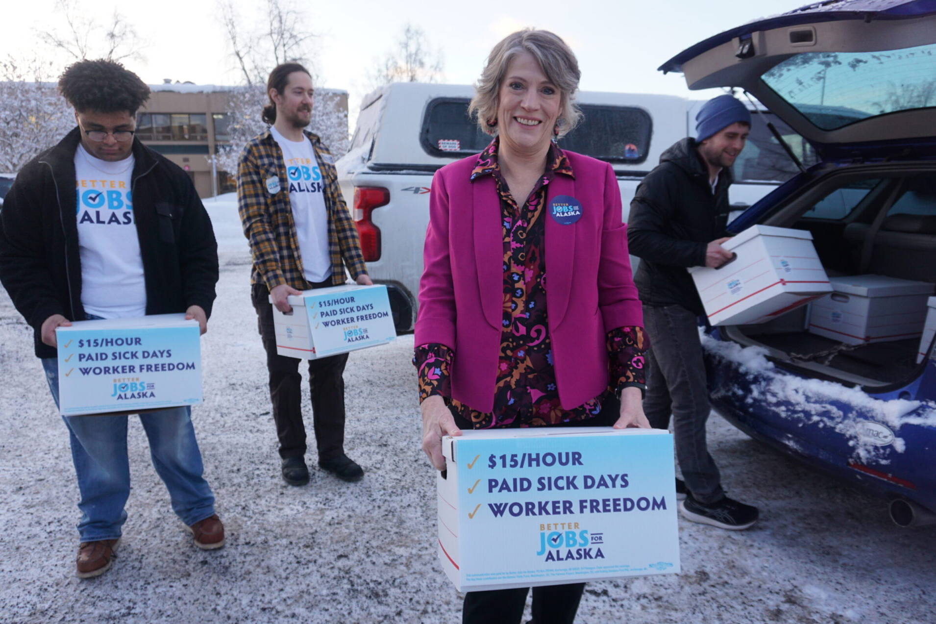 Joelle Hall, president of the Alaska AFL-CIO, carries a box of signed petitions for an increased minimum wage to be delivered to the Alaska Division of Elections on Tuesday. Hall is a leader of the campaign to pass a ballot initiative increasing workers’ minimum pay, mandating paid sick leave and ensuring that workers are not required to hear employers’ political, religious or anti-union messages. Behind her are other advocates for the ballot initiative. (Yereth Rosen/Alaska Beacon)