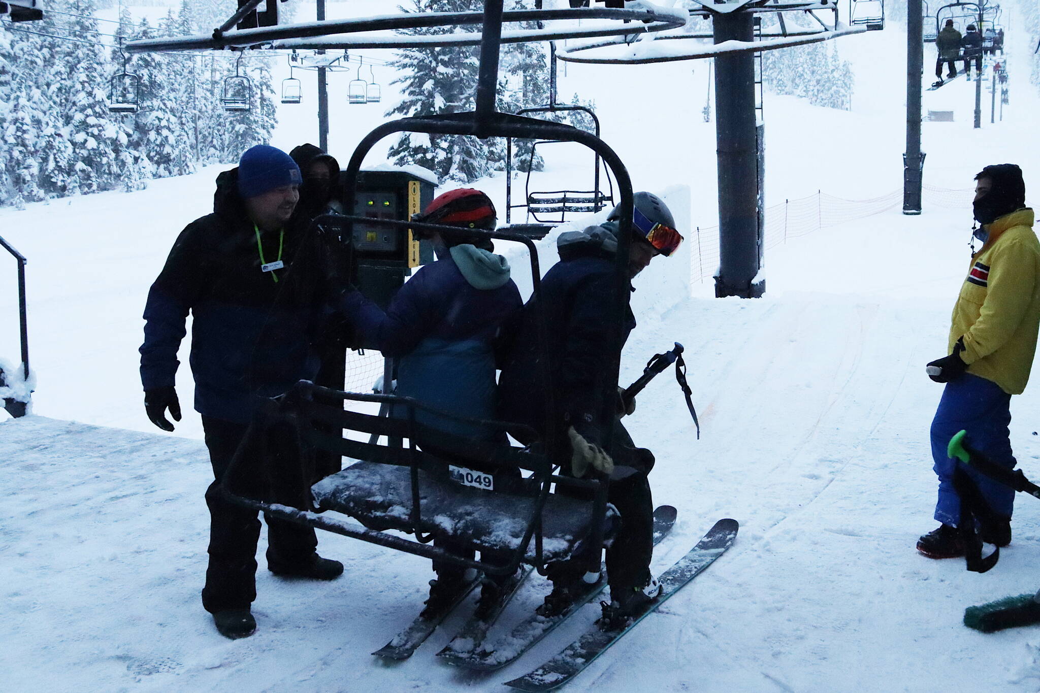 An Eaglecrest Ski Area lift operator helps skiers on Dec. 20. A study published earlier this month states the average wage of $13.06 for Eaglecrest lift operators and attendants is 25% below the average at U.S. ski resorts. (Mark Sabbatini / Juneau Empire file photo)
