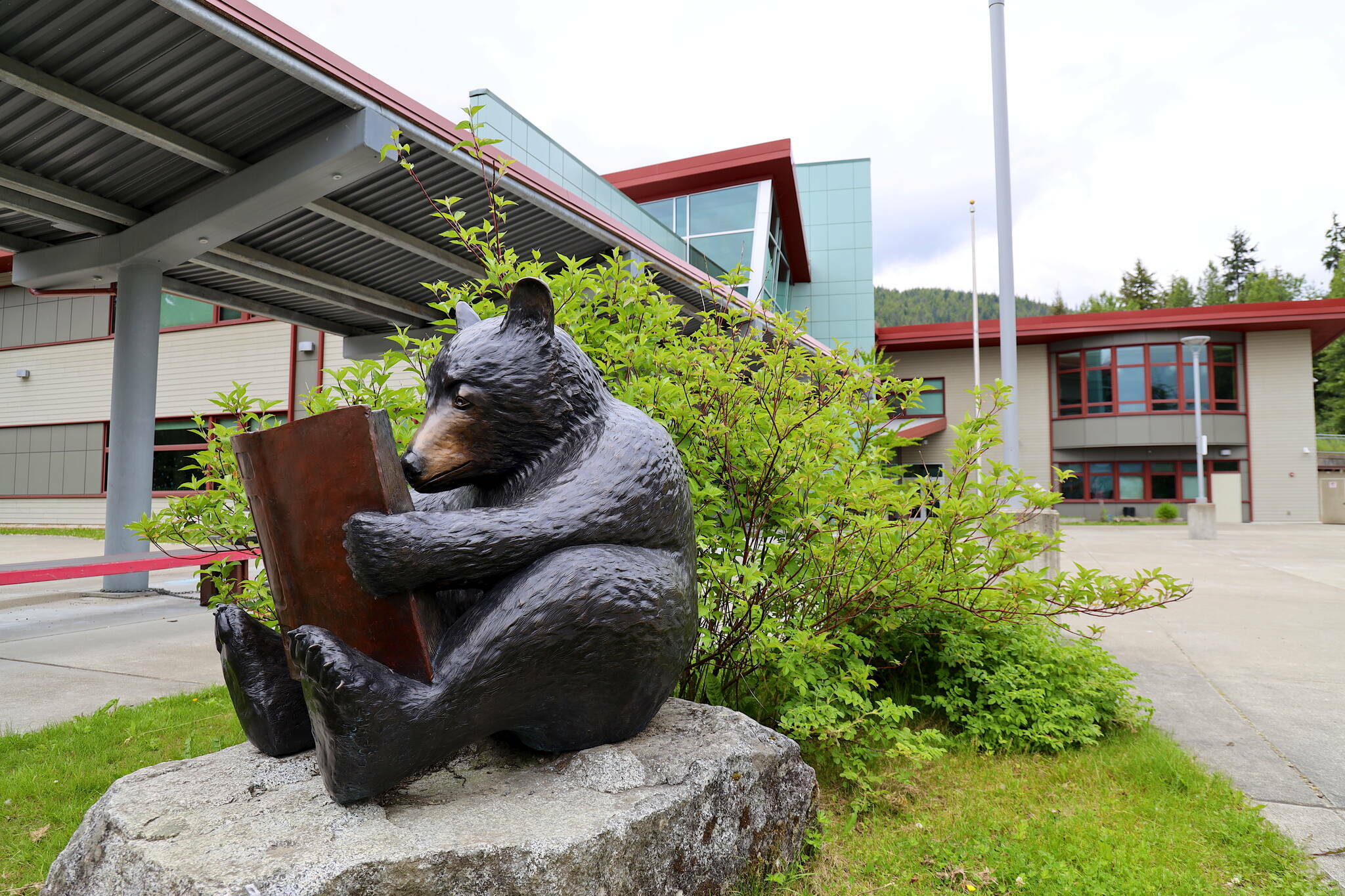 A sculpture of a bear reading a book is seen in front of Auke Bay Elementary School on July 12, 2023. The Juneau Board of Education is considering a range of drastic options, including consolidating schools, to help resolve a $9.5 million deficit this year. (Clarise Larson / Juneau Empire file photo)