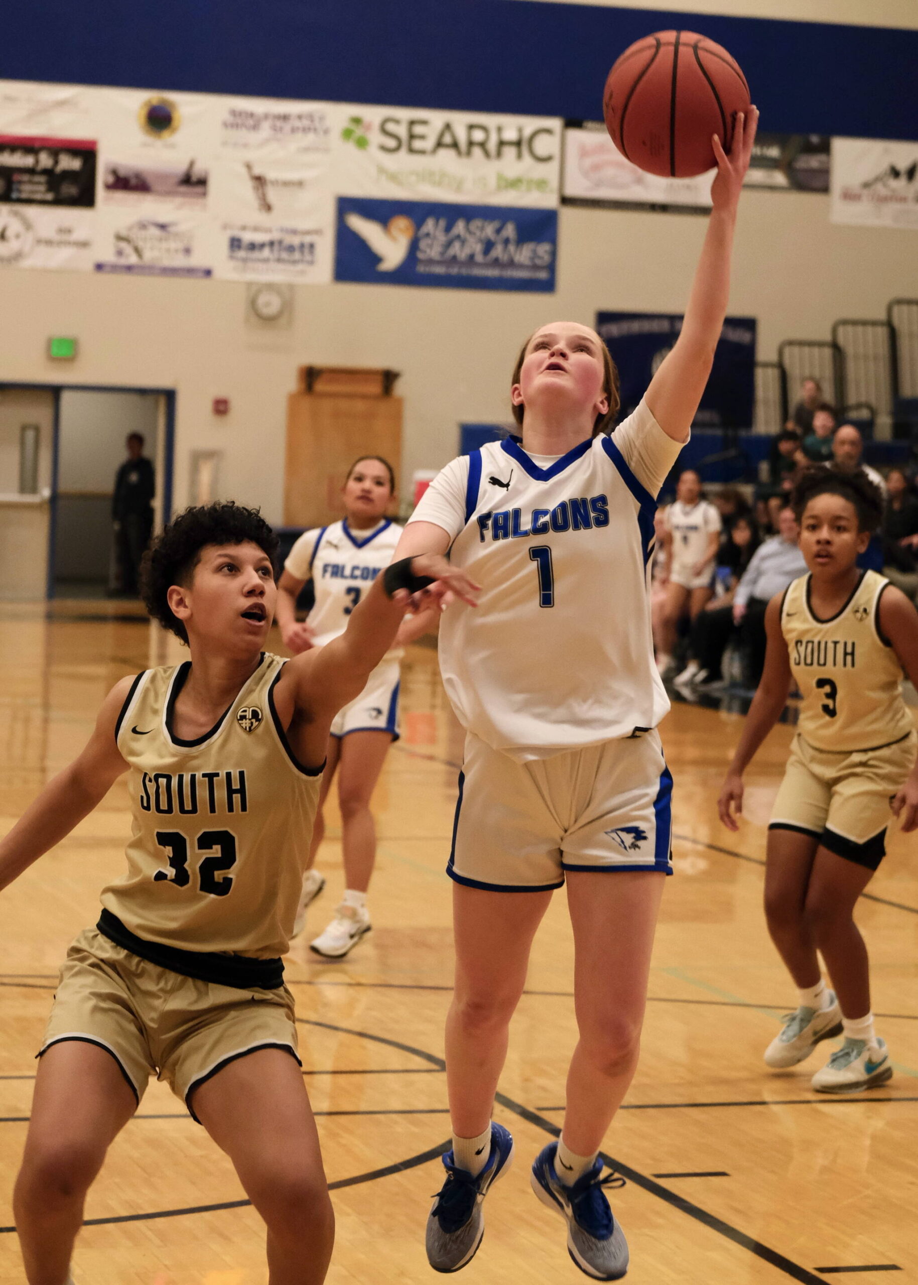 Thunder Mountain sophomore Cambry Lockhart (1) scores over South Anchorages Isa Costadasily (32) during the Falcons 73-37 win over the Wolverines on Thursday at the Thunderdome. (Klas Stolpe / For the Juneau Empire)