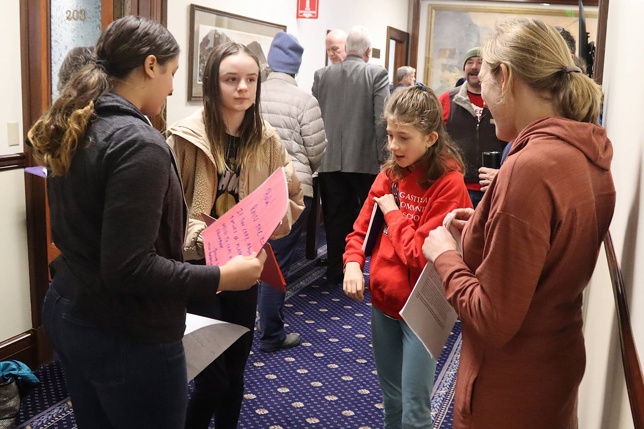From left, Bela Pyare, 13, Josie Elfers, 11, Nayeli Hood, 11, and Emily Ferry, a member of the Alaska Association of School Boards, discuss their testimony about a board-based education bill in a hallway at the Alaska State Capitol during a House Rule Committee meeting on Saturday. (Mark Sabbatini / Juneau Empire)