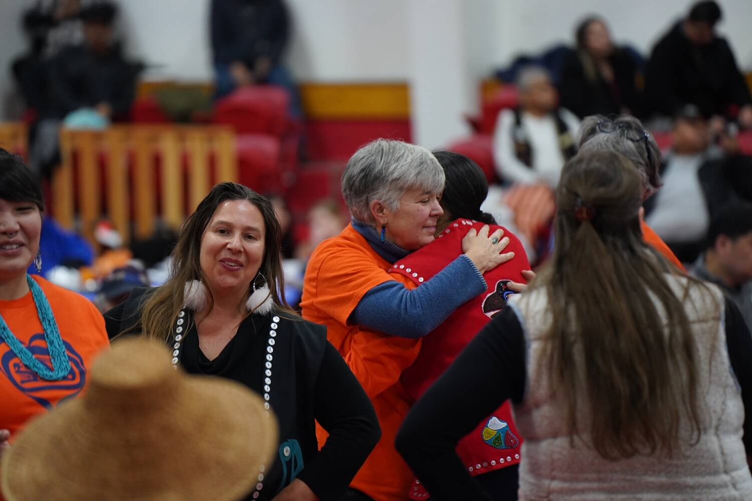 Cathy Walling of the Alaska Quaker Friends hugs Jamiann S’eiltin Hasselquist in Kake, while Ati Nasiah of the non-profit Haa Tóoch Lichéesh smiles in the foreground on Jan. 19. (Photo by Shaelene Grace Moler)