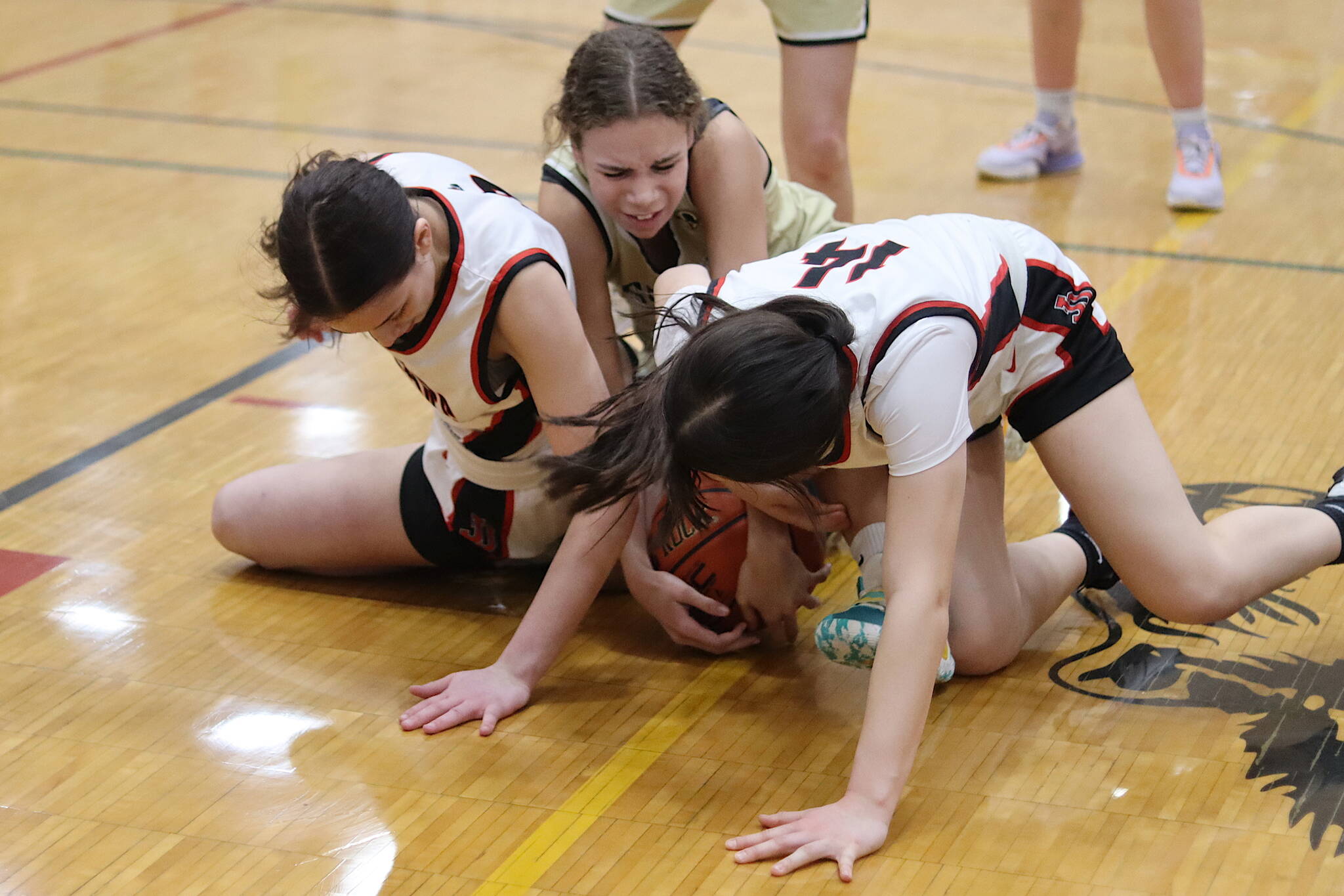Nadia Wilson, left, and Layla Tokuoka, right, of Juneau-Douglas High School: Yadaa.at Kalé fight for possession of the ball with Skylar Morris of South Anchorage High School during Saturday’s game at JDHS. (Mark Sabbatini / Juneau Empire)