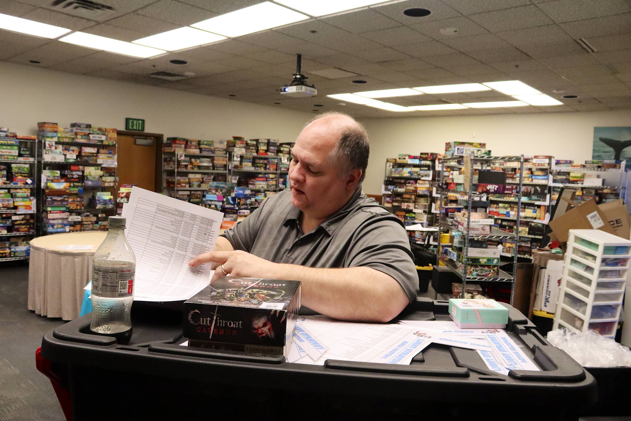 Jared Yancy checks off games on an inventory list in preparation Thursday for the Platypus-Con Board and Card Game Extravaganza, scheduled Friday through Sunday at Centennial Hall. (Mark Sabbatini / Juneau Empire)