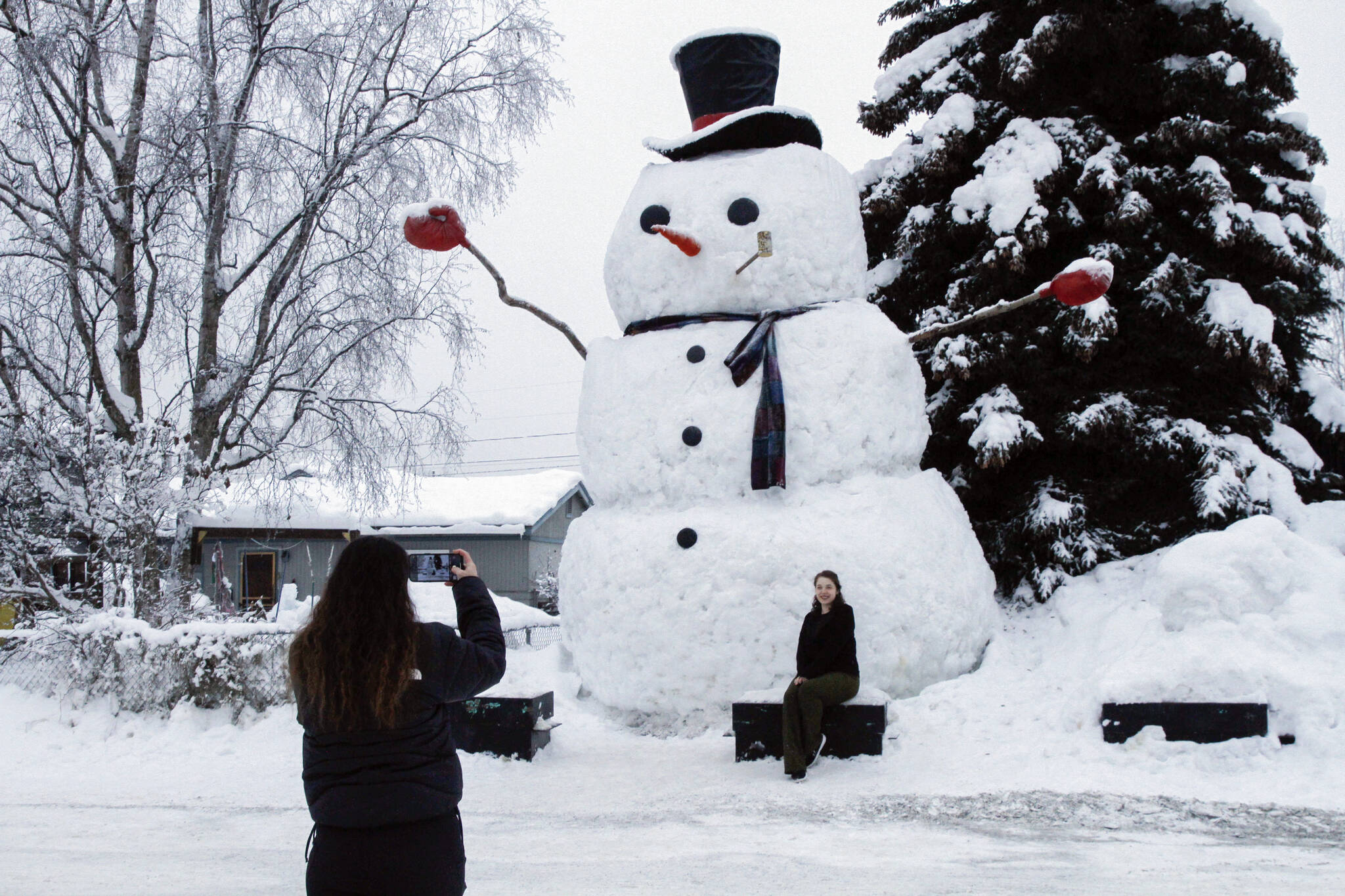 Isil Mico takes a photo of her sister-in-law Oznur Mico in front of Snowzilla, a snowman measuring more than 20 feet tall, in Anchorage, Alaska on Jan. 10, 2024. A recent storm dropped nearly 16 inches of snow on Anchorage, bringing the seasonal total to over 103 inches. It’s the earliest Alaska’s largest city has reached the 100-inch mark. (AP Photo/Mark Thiessen, File)