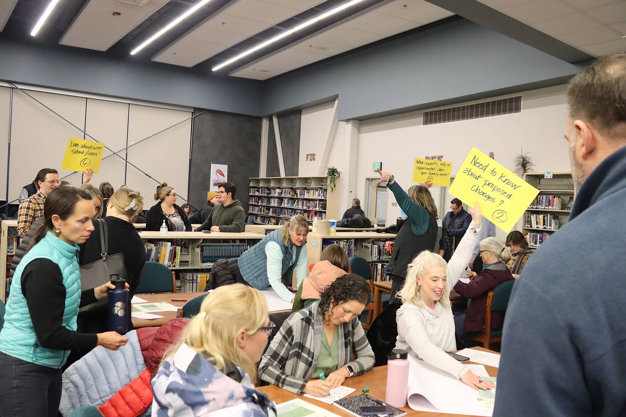Juneau School District leaders hold up signs for subgroups they are leading during a Community Budget Input Session at Thunder Mountain High School on Wednesday night. (Mark Sabbatini / Juneau Empire)