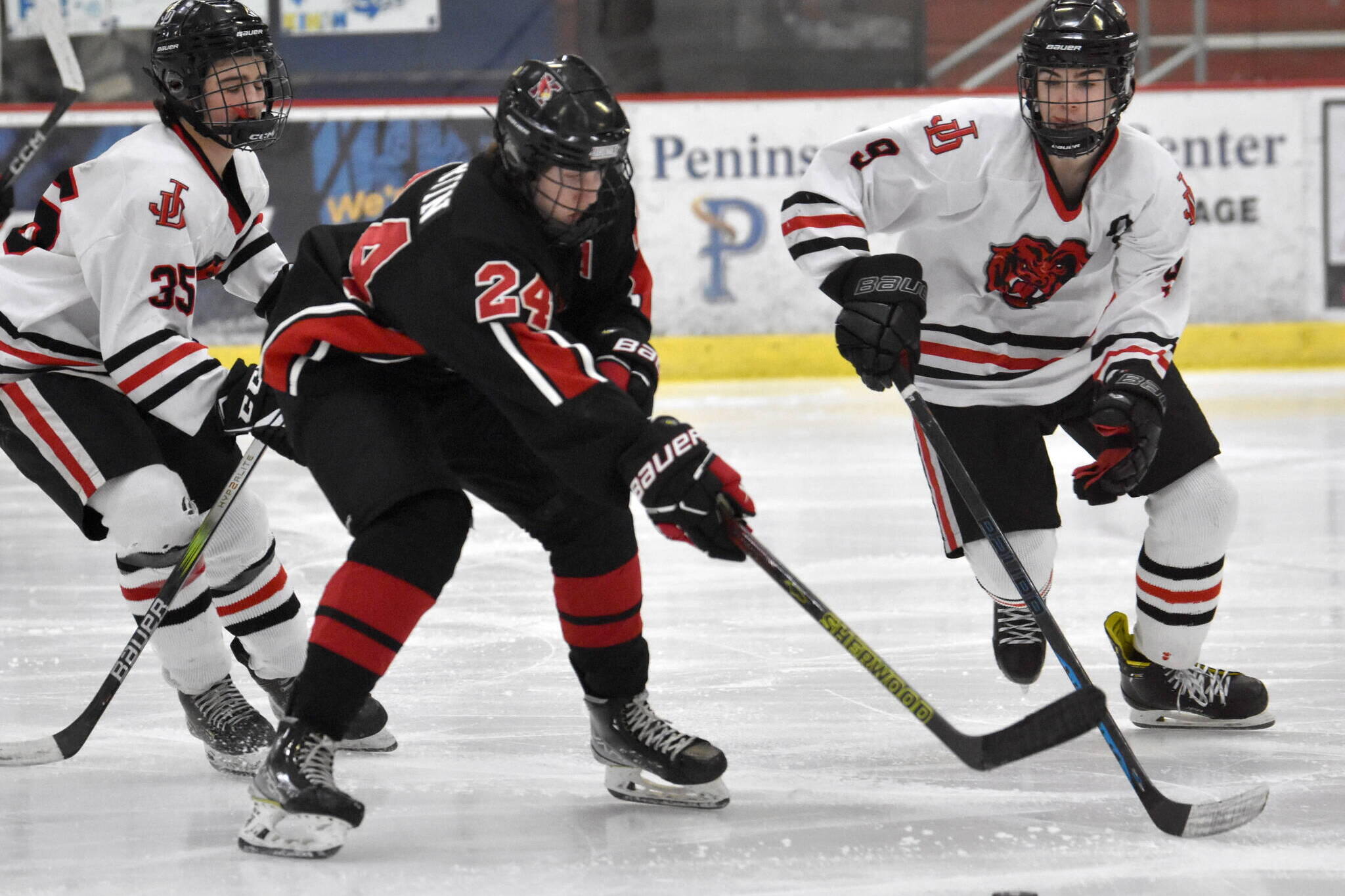 Kenai Central’s Avery Martin tries to split Juneau-Douglas High School: Yadaa.at Kale’s Dylan Sowa and Camden Kovach on Thursday at the Division II state hockey tournament at the Soldotna Regional Sports Complex in Soldotna. (Jeff Helminiak/Peninsula Clarion)