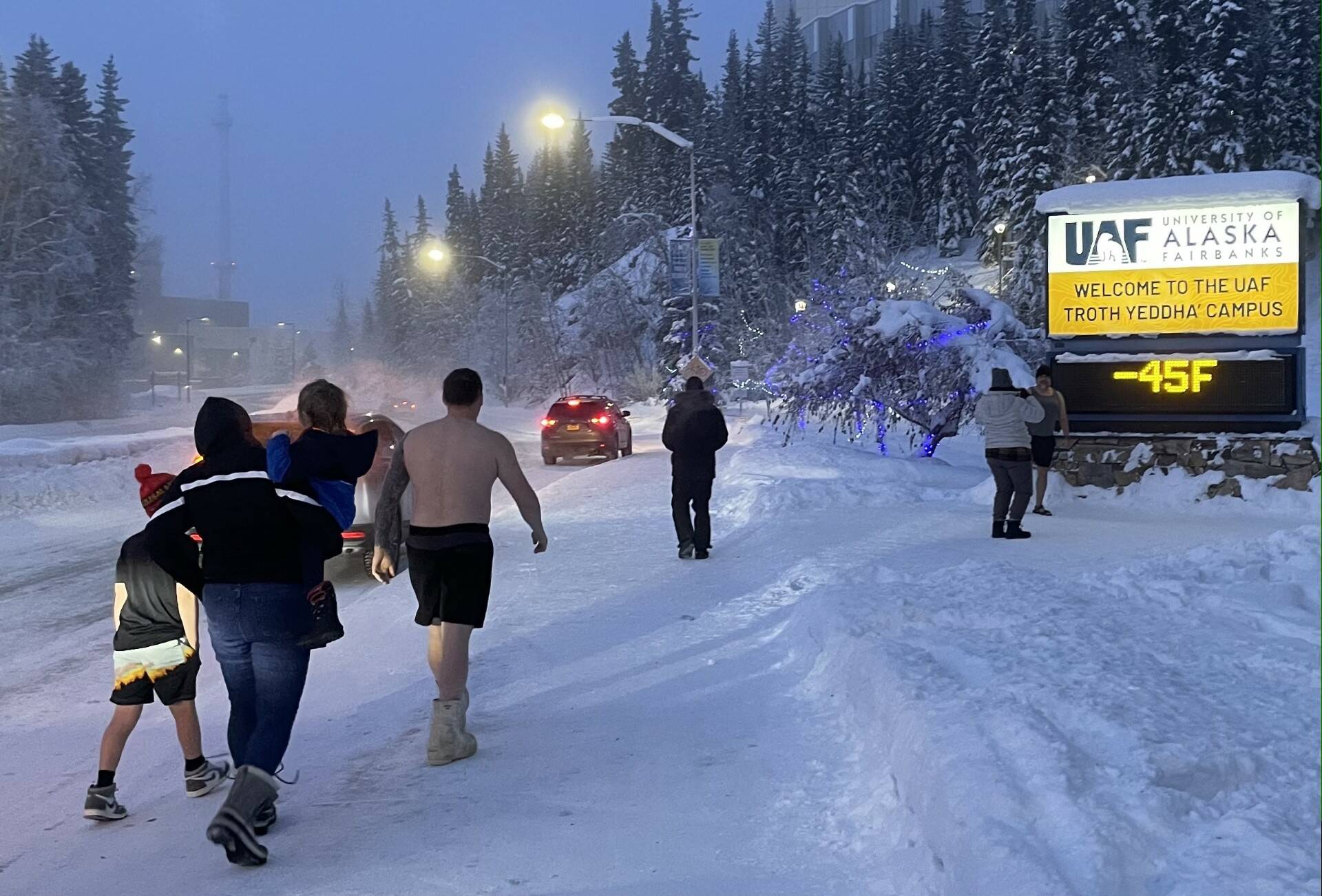 Fairbanks residents engage in a favorite cold-weather activity of taking photographs of themselves in front of the University of Alaska Fairbanks time-and-temperature sign on the morning of Jan. 27, 2024. (Photo by Ned Rozell)
