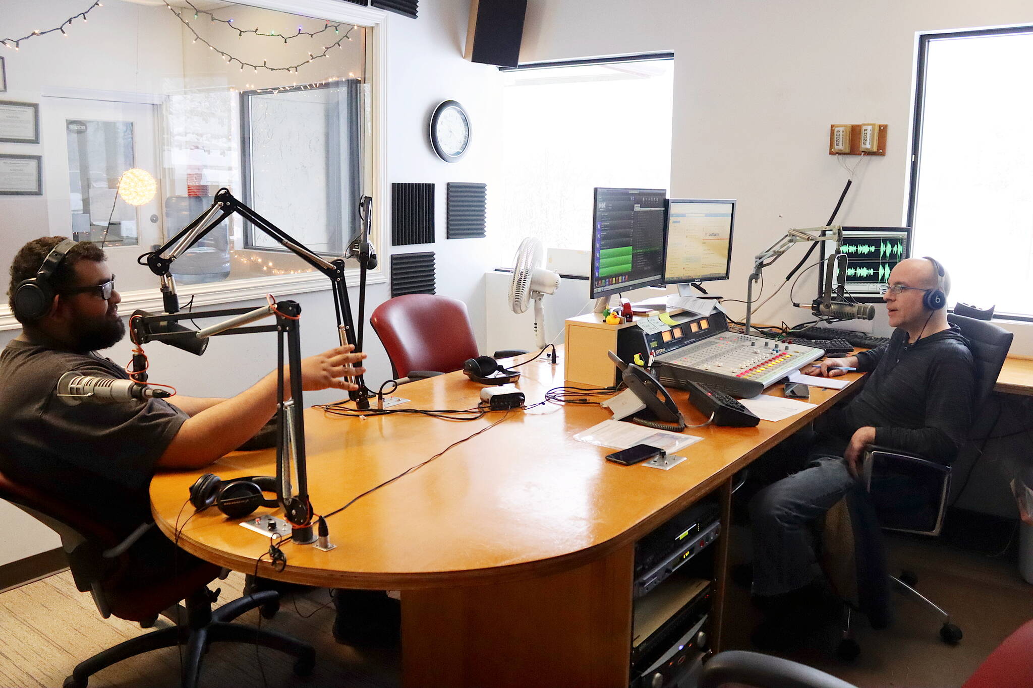 Jordan Lewis (left), news director for Local First Media Group, discusses the day’s top news stories with Wade Bryson during the final live broadcast of KINY-AM’s “Problem Corner” on Friday. (Mark Sabbatini / Juneau Empire)