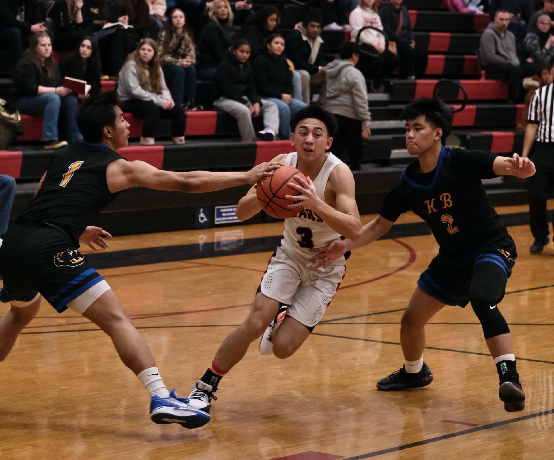 Juneau-Douglas High School: Yadaa.at Kalé senior Alwen Carrillo (3) is defended by Kodiak senior Aron Paguio (1) and junior Bubba Basuel (2) during the Crimson Bears 75-50 win over the Bears on Saturday at the George Houston Gymnasium. (Klas Stolpe/For the Juneau Empire)
