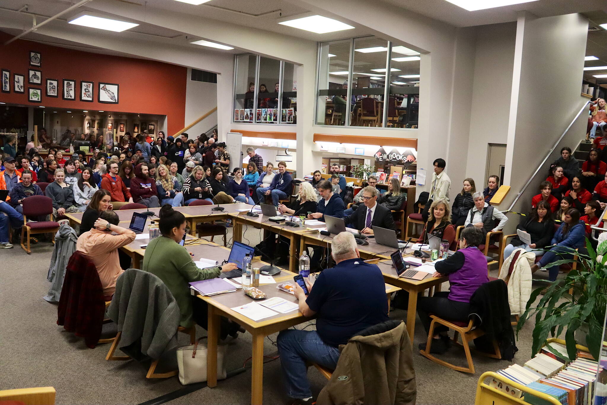 A crowd overflows the library at Juneau-Douglas High School: Yadaa.at Kalé on Thursday night as school board members meet to select a consolidation option to help resolve the Juneau School District’s budget crisis. (Mark Sabbatini / Juneau Empire)