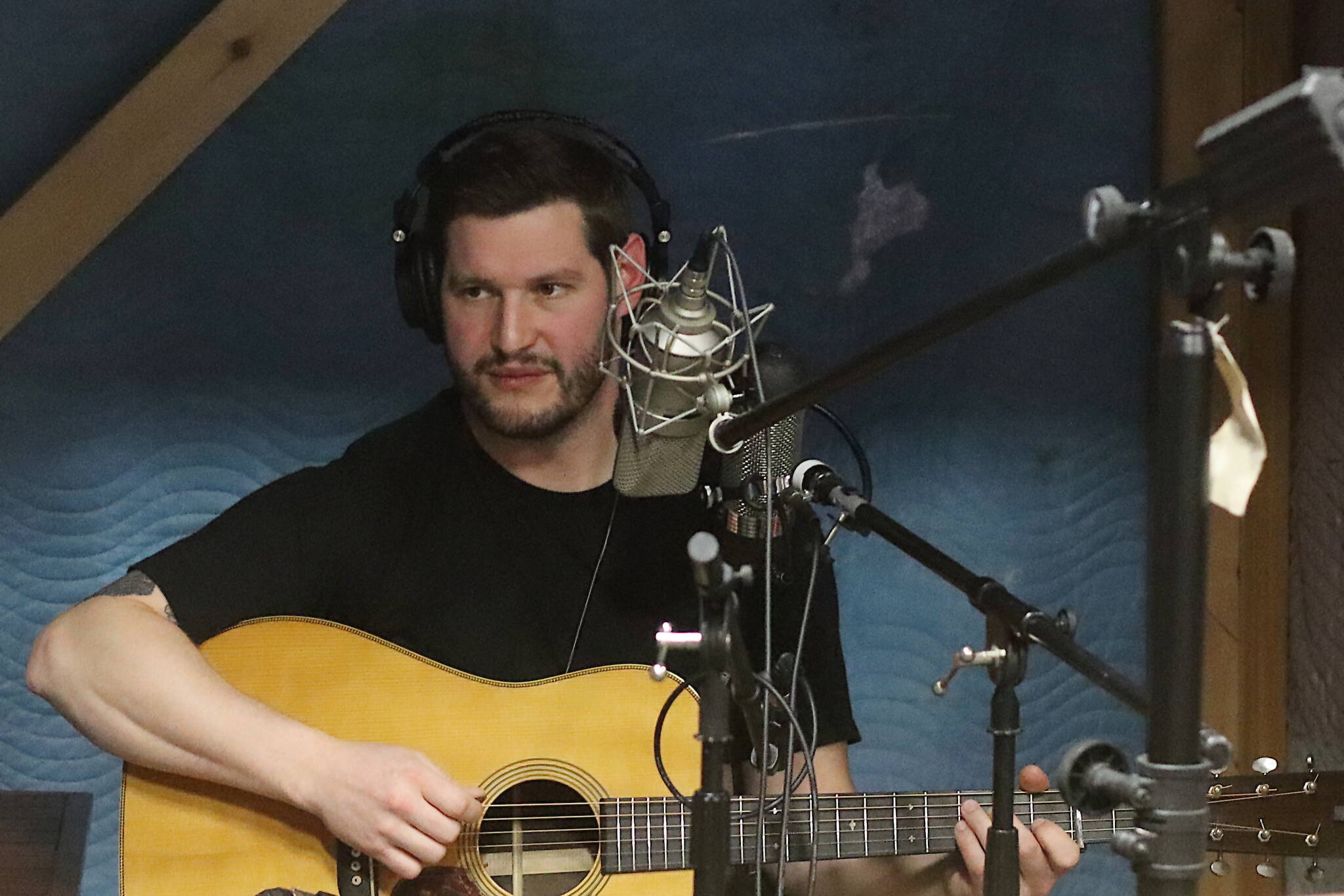 Josh Fortenbery records a song from his debut album “No Such Thing as Forever” while sitting in an improvised sound isolation booth at the KTOO studios in early 2023. (Mark Sabbatini / Juneau Empire)