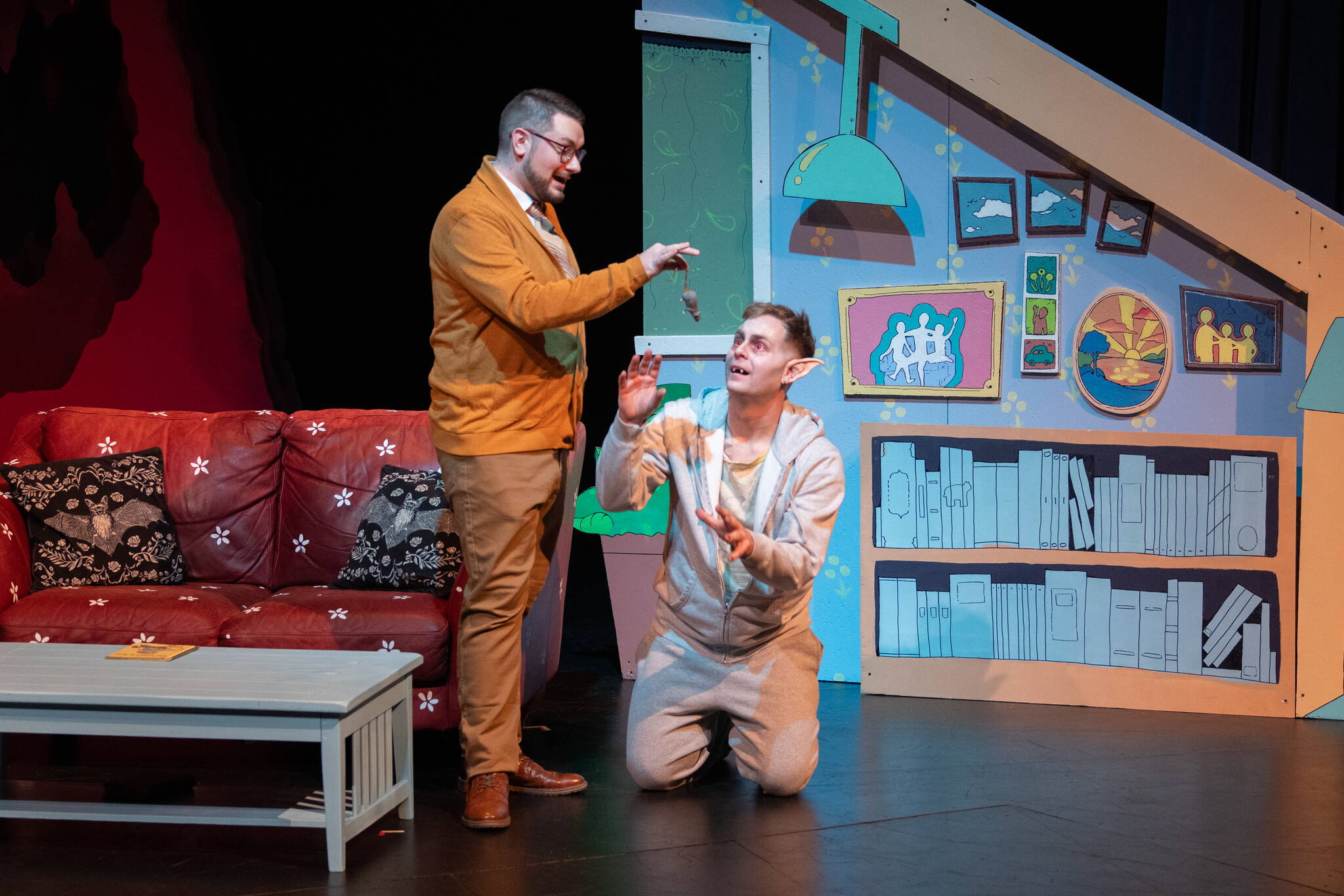 Steven Arends (left) feeds Joshua Midgett in Juneau Ghost Light Theatre’s production of “Bat Boy: The Musical,” which is being staged through March 17 at Thunder Mountain High School. (Cam Byrnes/ Juneau Ghost Light Theatre)