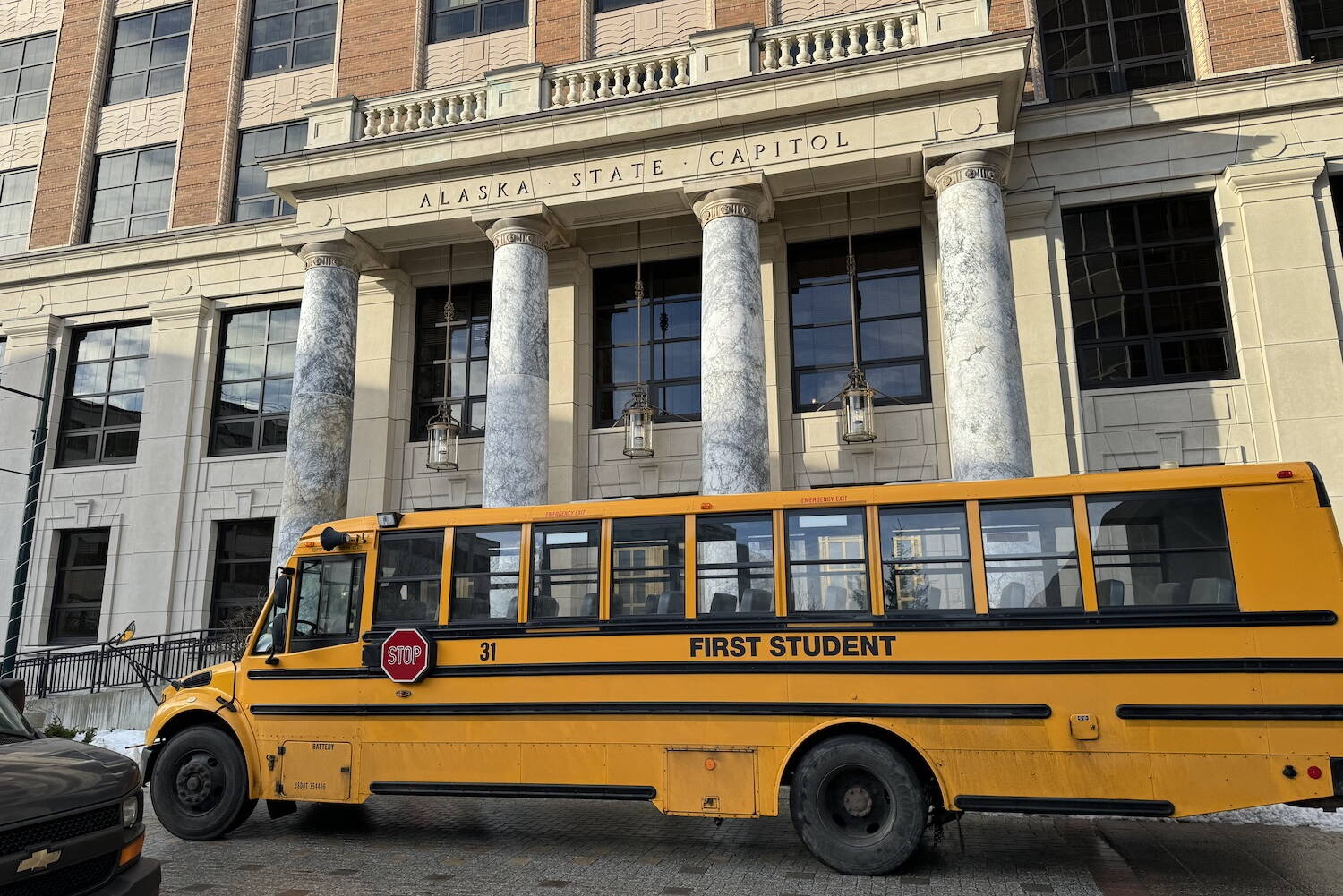A school bus passes in front of the Alaska State Capitol on Feb. 6. (James Brooks/Alaska Beacon)
