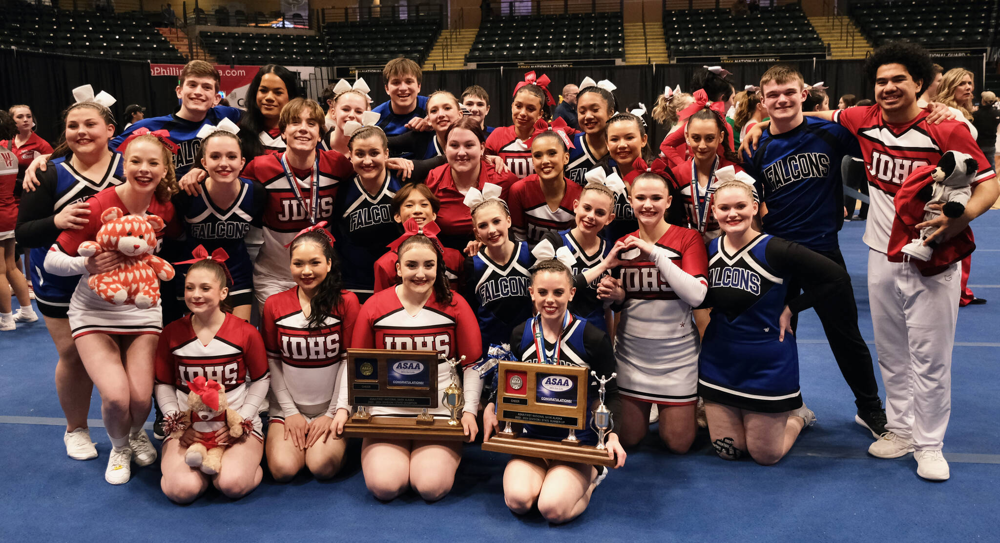 The Juneau-Douglas High School: Yadaa.at Kalé Crimson Bears and Thunder Mountain Falcons cheer teams pose with their champion and runner-up trophies on Tuesday at the 2024 ASAA/First National Bank Alaska Cheer State Championships at the Alaska Airlines Center in Anchorage. (Klas Stolpe, For the Juneau Empire)