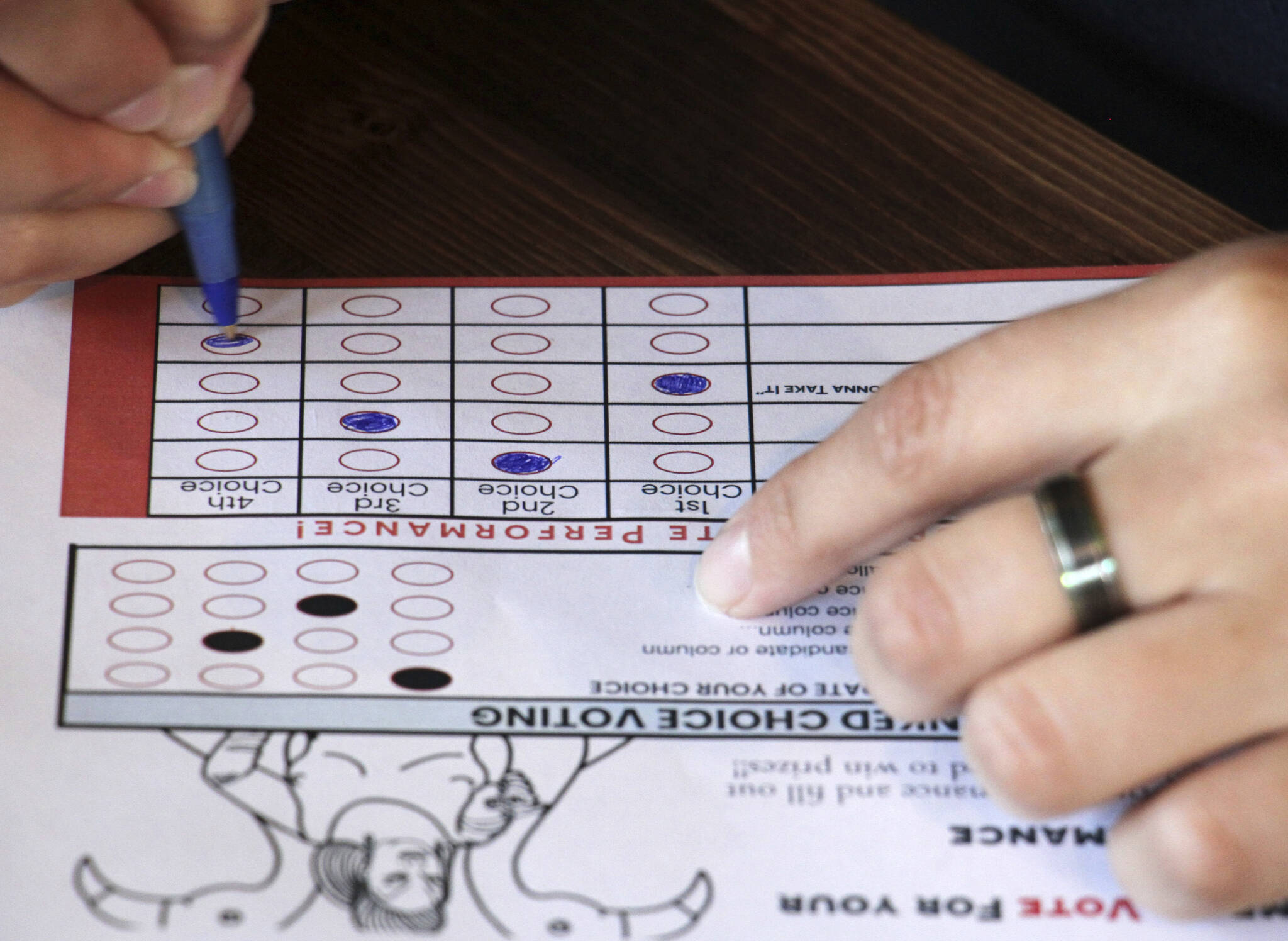 This July 28, 2022, photo shows a person completing a ballot in a mock election at Cafecito Bonito in Anchorage, where people ranked the performances by drag performers, one of the education efforts about ranked choice voting in elections that year. (Mark Thiessen/AP file photo)