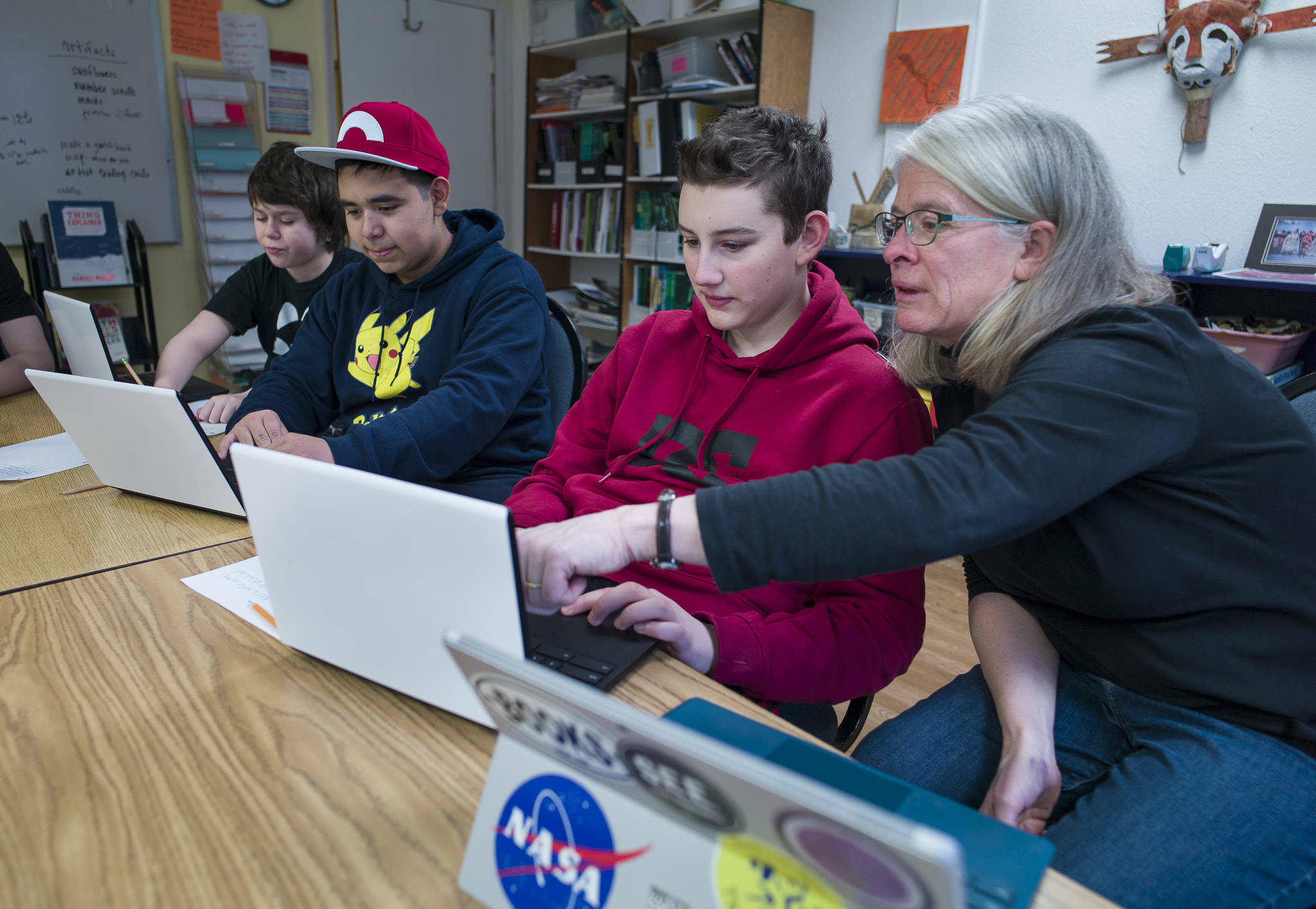 Math Specialist Brenda Taylor helps eighth-graders Fisher Lee, right, and Jorge Cordero, center, and sixth-grader Joshua Kessler with their coding project at the Juneau Community Charter School on Wednesday, Jan. 10, 2018. The school celebrated its 20th anniversary that year. (Michael Penn / Juneau Empire file photo)
