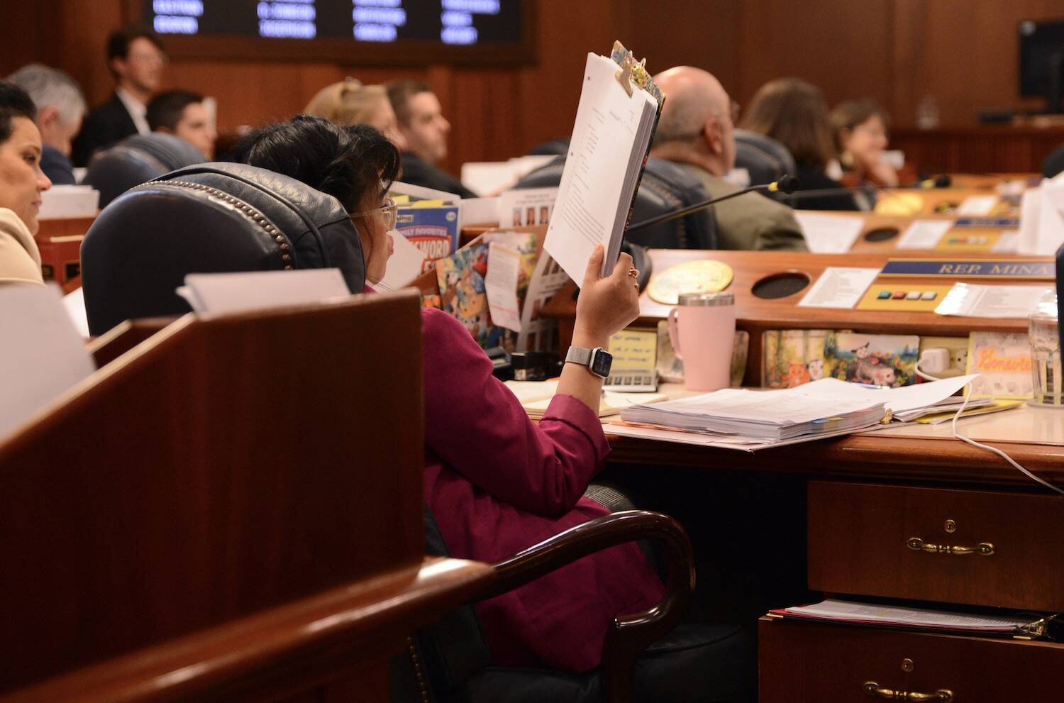 Rep. Genevieve Mina, D-Anchorage, stares at a pile stack of budget amendments on Tuesday. (James Brooks/Alaska Beacon)