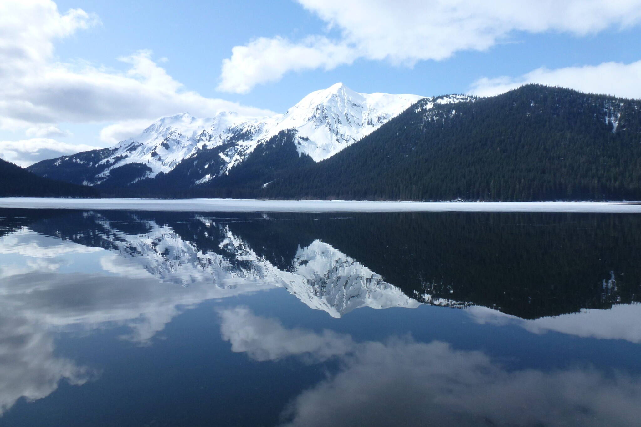 The sky and mountains are reflected in the water on April 5, 2012, at the Kootznoowoo Wilderness in the Tongass National Forest’s Admiralty Island National Monument. Conservation organizations bought some private land and transferred it to the U.S. Forest Service, resulting in an incremental expansion of the Kootznoowoo Wilderness and protection of habitat important to salmon and wildlife. (Photo by Don MacDougall/U.S. Forest Service)