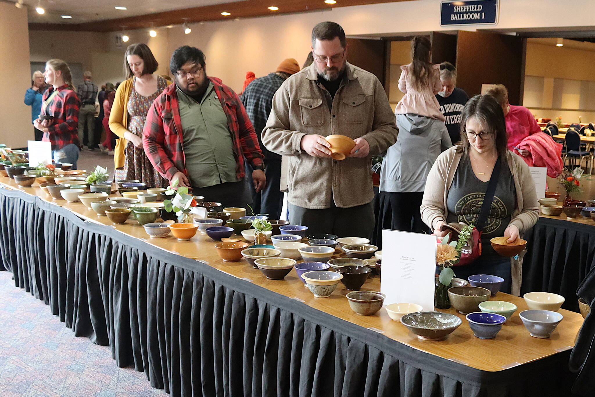 Bailey Woolfstead, right, and her companion Garrett Dunbar examine the selection of ceramic and wood dishes on display at the annual Empty Bowls fundraiser on behalf of the Glory Hall at Centennial Hall on Sunday. (Mark Sabbatini / Juneau Empire)