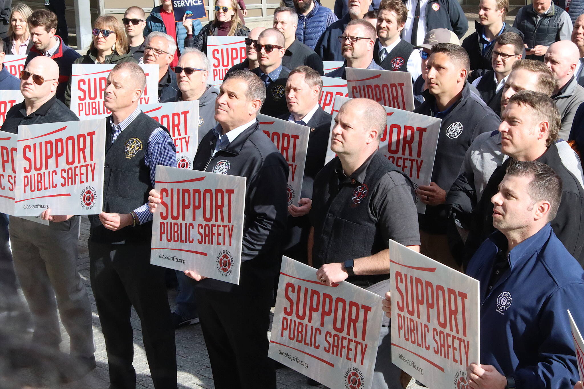 Public safety officials and supporters hold signs during a protest at the Alaska State Capitol on Tuesday afternoon calling for the restoration of state employee pensions. (Mark Sabbatini / Juneau Empire)