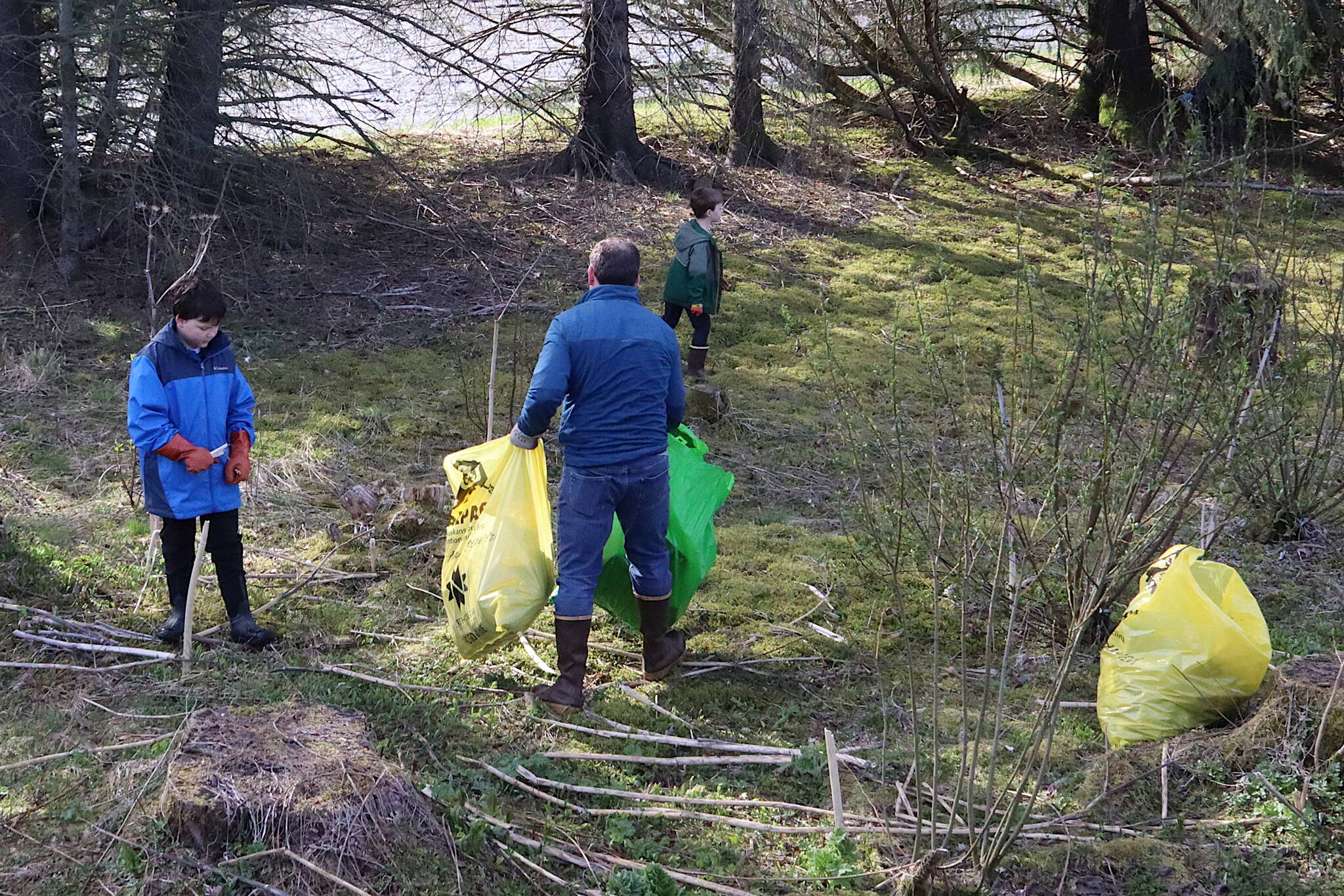 Nils Andreassen and his sons Amos, 7, and Axel, 11, pick up trash in the Lemon Creek area during the annual Litter Free community cleanup on Saturday morning. (Mark Sabbatini / Juneau Empire)