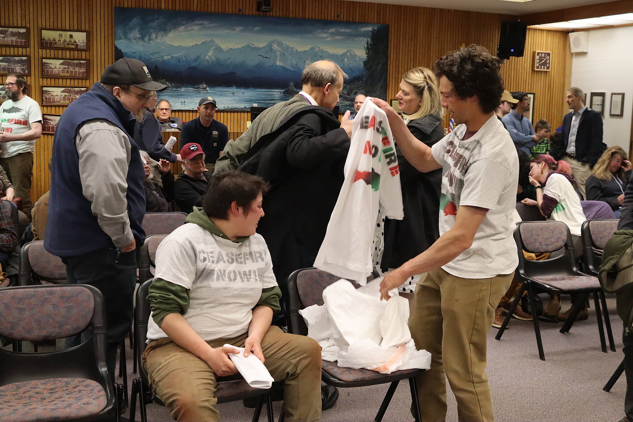 Juneau residents calling for a ceasefire in Gaza put on t-shirts with slogans declaring their cause before testifying on a resolution calling for “a bilateral peace agreement in Israel and Palestine” considered by the Juneau Assembly on Monday night. (Mark Sabbatini / Juneau Empire)