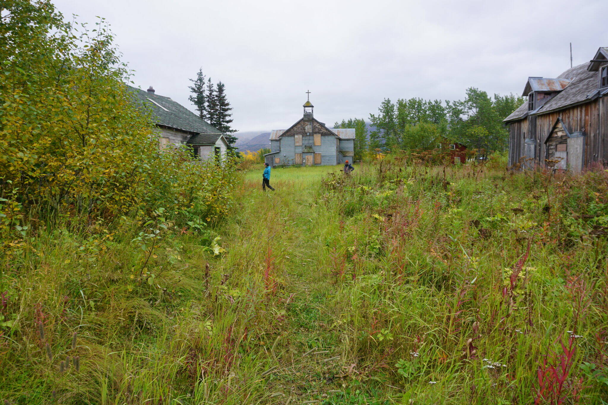 Visitors on Sept. 4, 2021, stroll by the historic chapel and buildings used for classrooms and dormitories that remain standing at Pilgrim Hot Springs. The site was used as an orphanage for Bering Strait-area children who lost their parents to the 1918-19 influenza epidemic. Pilgrim Hot Springs is among the state’s 11 most endangered historic properties, according to an annual list released by Preservation Alaska. (Yereth Rosen/Alaska Beacon)