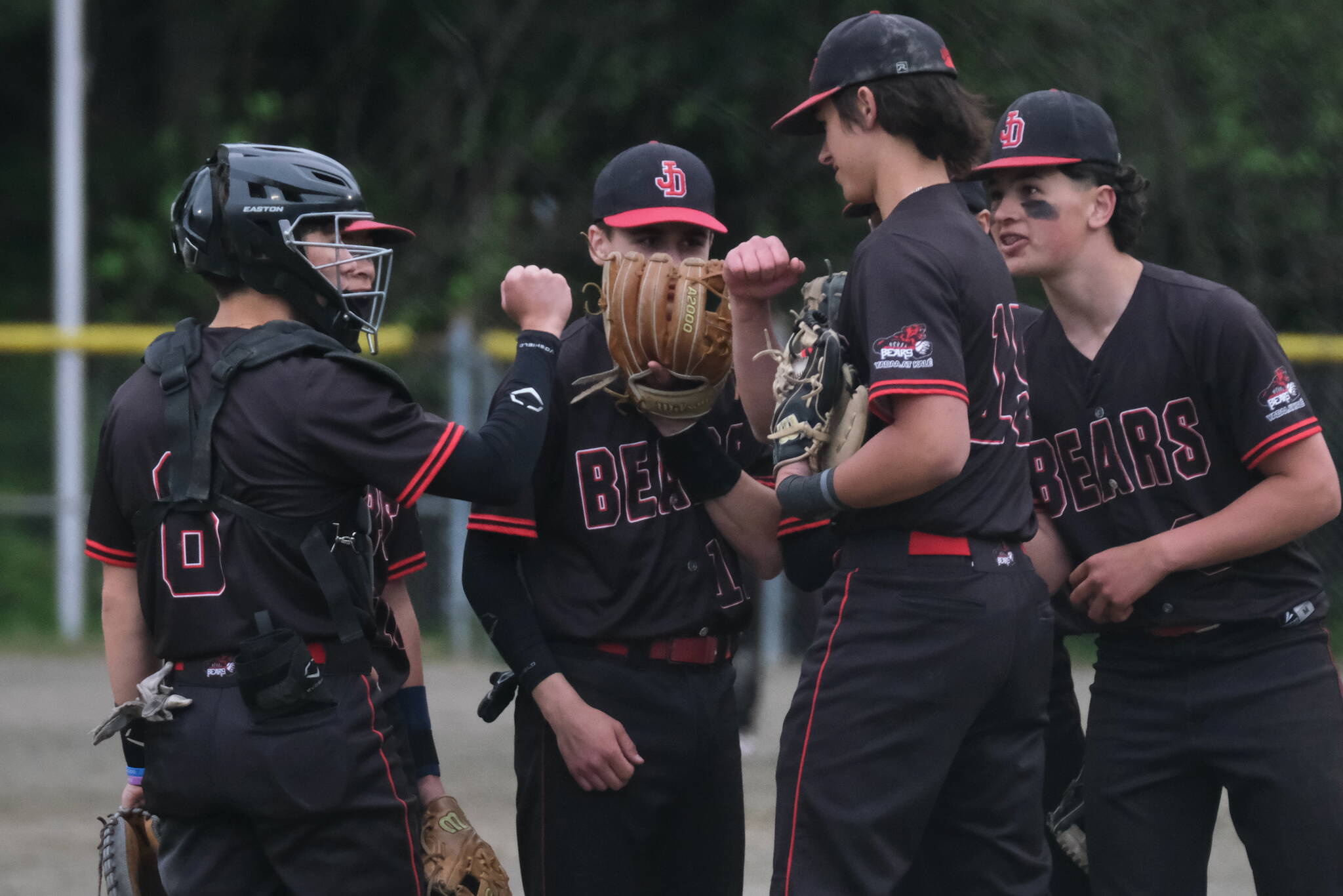 Juneau-Douglas High School: Yadaa.at Kalé senior battery Lamar Blatnick (catcher) and Landon Simonson (pitcher) bump fists on the mound with teammates as they begin their final home game at Adair-Kennedy Field on Saturday. (Klas Stolpe / For the Juneau Empire)