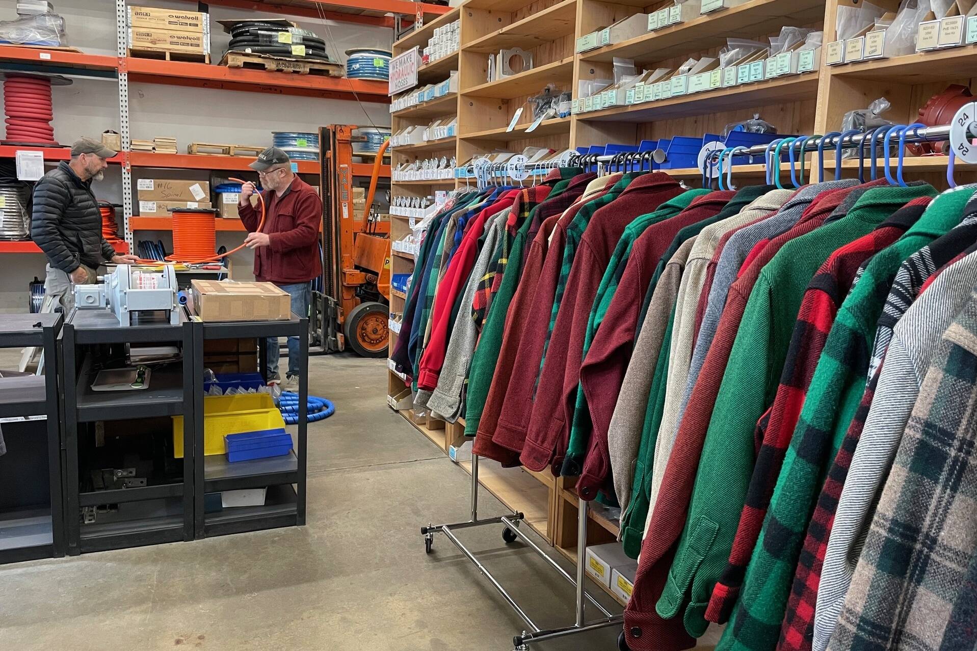 Tom Abbas discusses the hose his boat needs as shop owner and vintage halibut jacket provider Jim Geraghty shows his customer the options. Racks of dry-cleaned woolen jackets hang among the marine supply aisles in Gerahgty’s Lemon Creek business. (Laurie Craig / Juneau Empire)