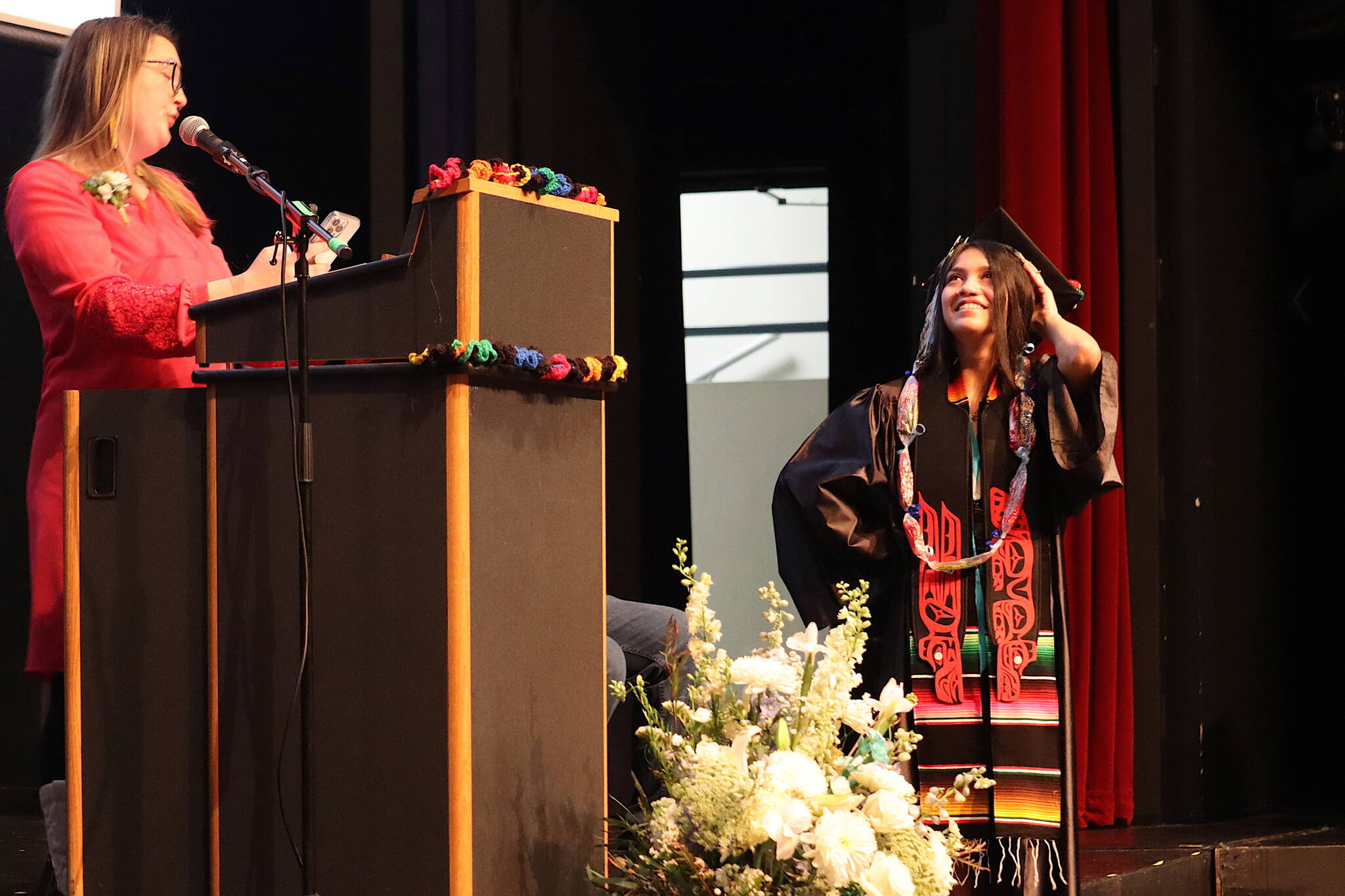 Sierra Guerro-Flores (right) listens to her advisor Electra Gardinier after being presented with her diploma at Yaaḵoosgé Daakahídi High School’s graduation ceremony Sunday in the Juneau-Douglas High School: Yadaa.at Kalé auditorium. (Mark Sabbatini / Juneau Empire)