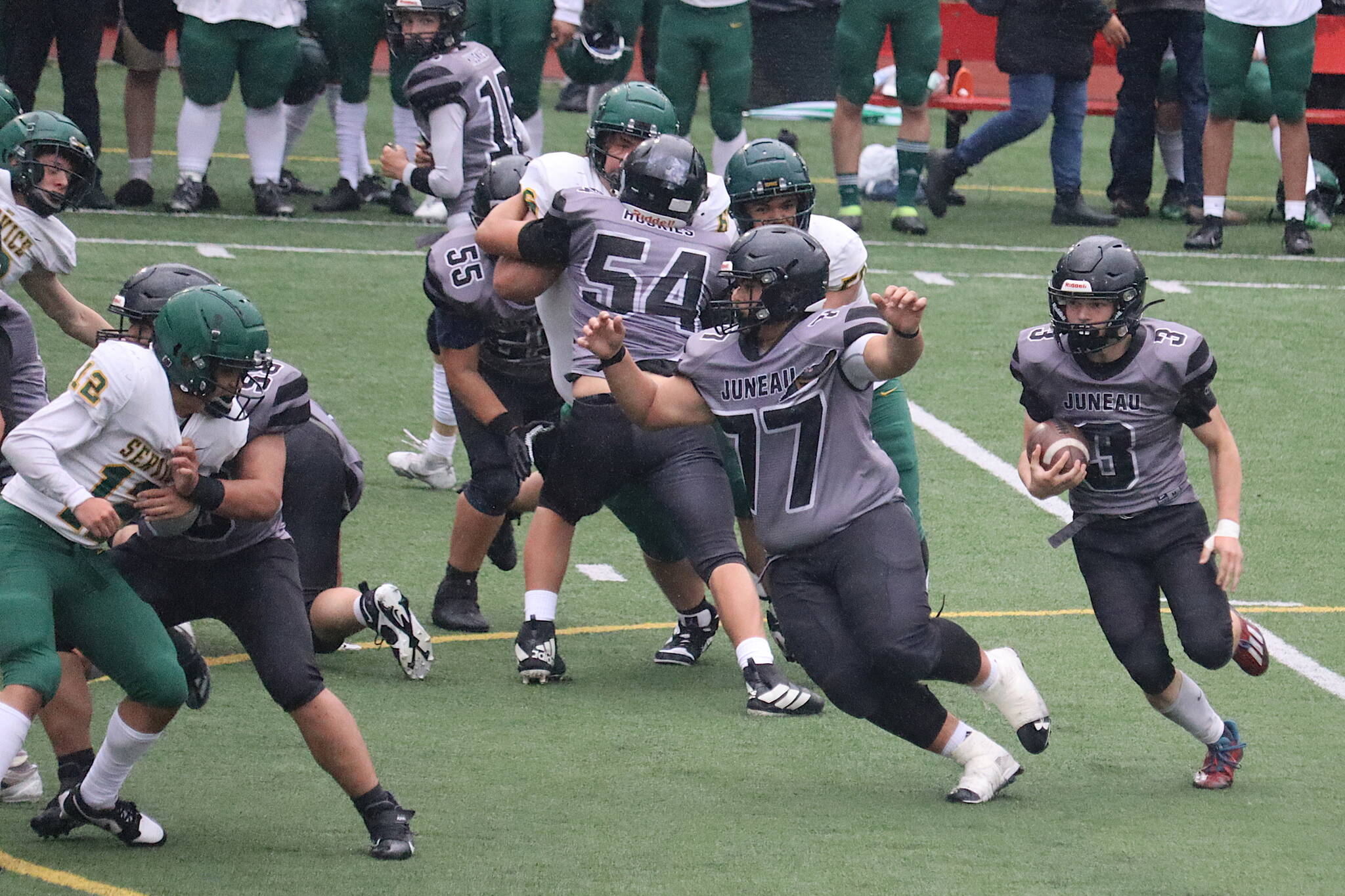Juneau-Douglas High School: Yadaa.at Kalé linemen Ricky Tupou, (77), Jonah Mahle (54), Walter Haube-Law (55) and Benny Zukas (58) block for Ethan Van Kirk (3) during Saturdays game against Service High School at Adair-Kennedy Memorial Park. (Mark Sabbatini / Juneau Empire)