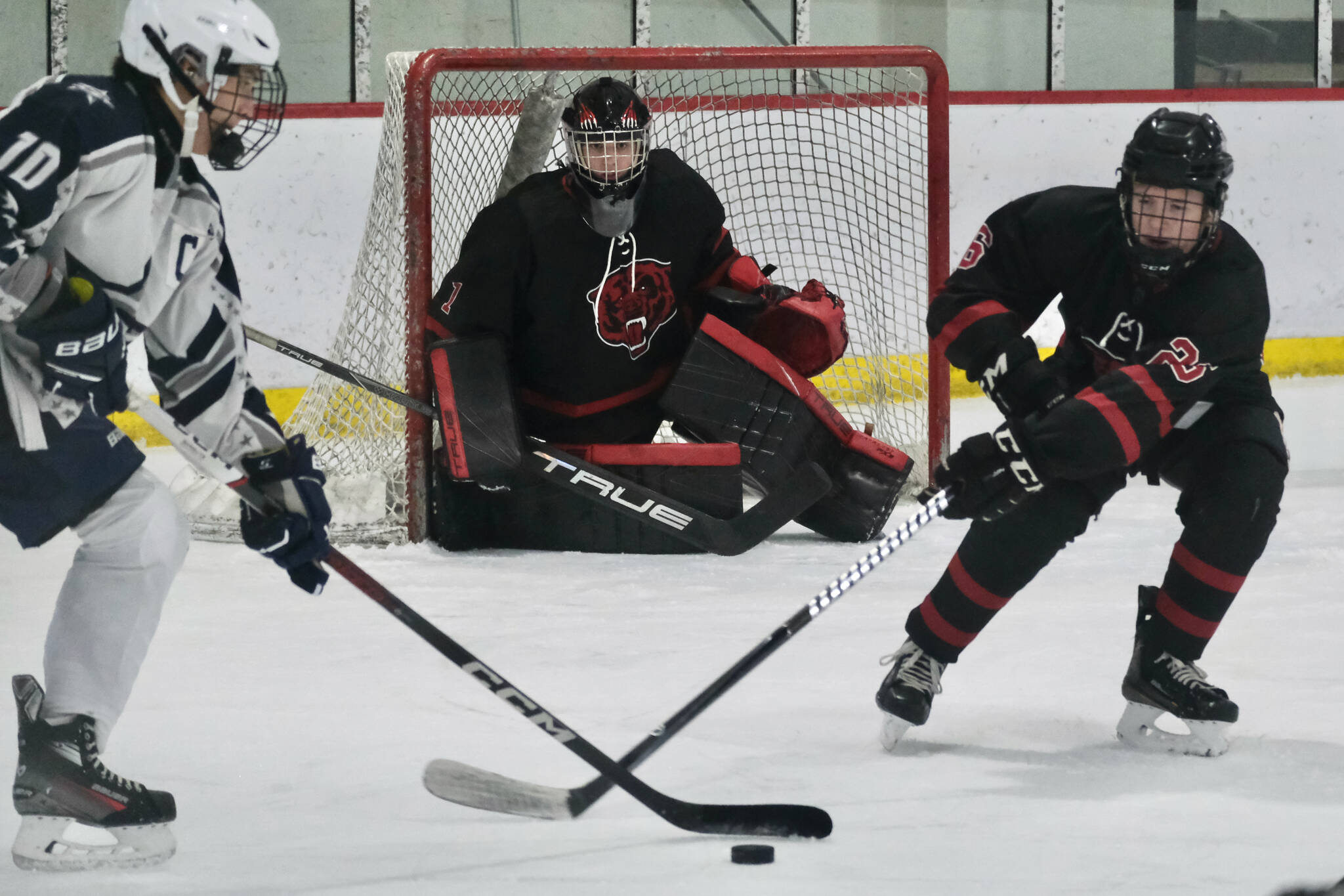 Juneau-Douglas High School: Yadaa.at Kalé senior goalie Caleb Friend (1) controls the net as Soldotnas Daniel Heath (10) and JDHS senior Loren Platt (26) play a puck during the Crimson Bears 2-0 win over the Stars on Saturday at Treadwell Ice Arena. (Klas Stolpe / Juneau Empire)