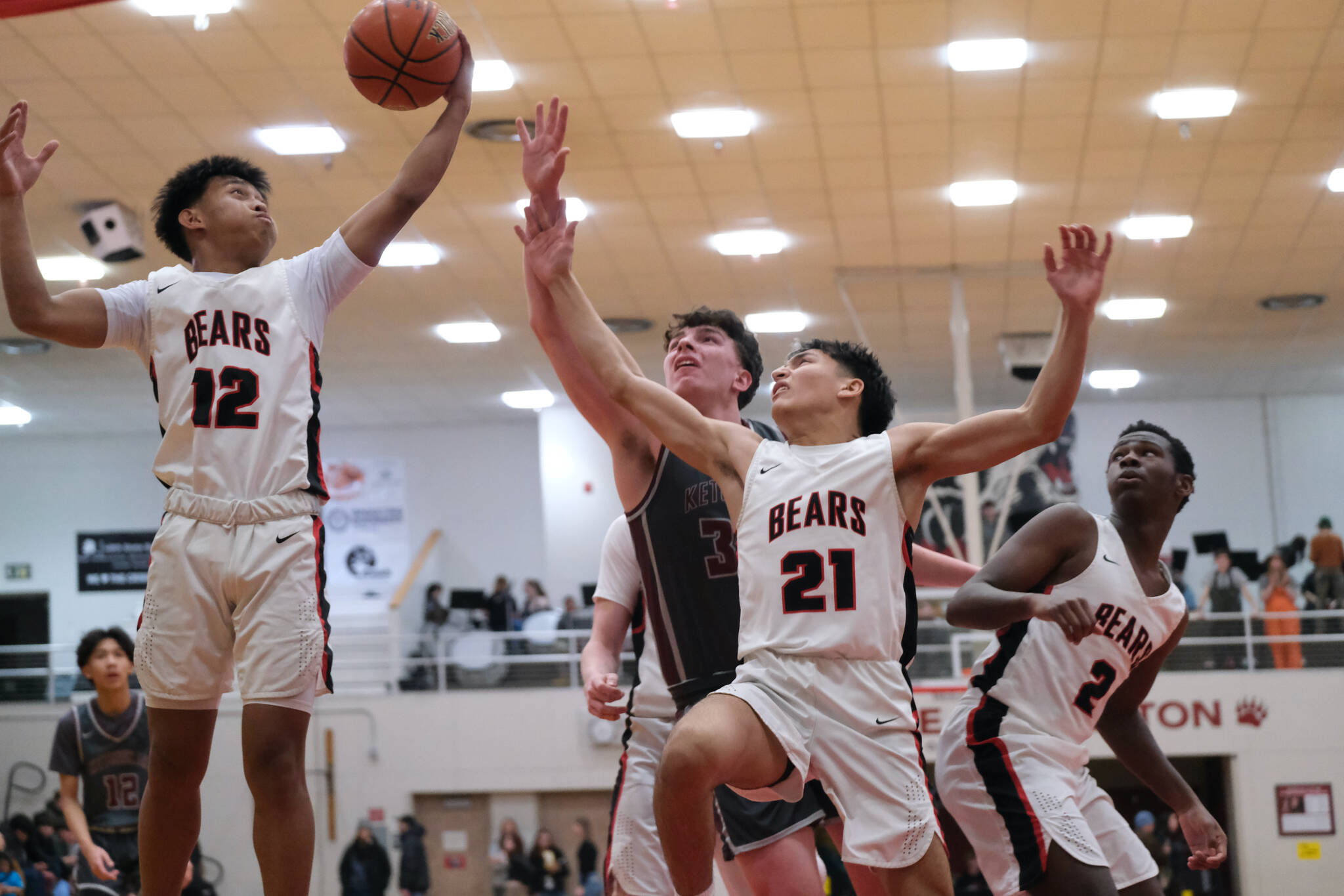 Juneau-Douglas High School: Yadaa.at Kalé juniors Joren Gasga (12) and Tyler Frisby (21) and senior Ahmir Parker (2) rebound with Ketchikan senior Marcus Stockhausen during the Crimson Bears 70-63 loss to the Kings on Saturday at the George Houston Gymnasium in Juneau. (Klas Stolpe / Juneau Empire)